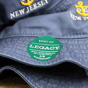 The Legacy Sticker on the Ocean City Anchor New Jersey Wordmark Bucket Hat | Slate Blue Bucket Hat