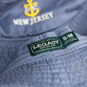 The Legacy Tag on the Ocean City Anchor New Jersey Wordmark Bucket Hat | Slate Blue Bucket Hat
