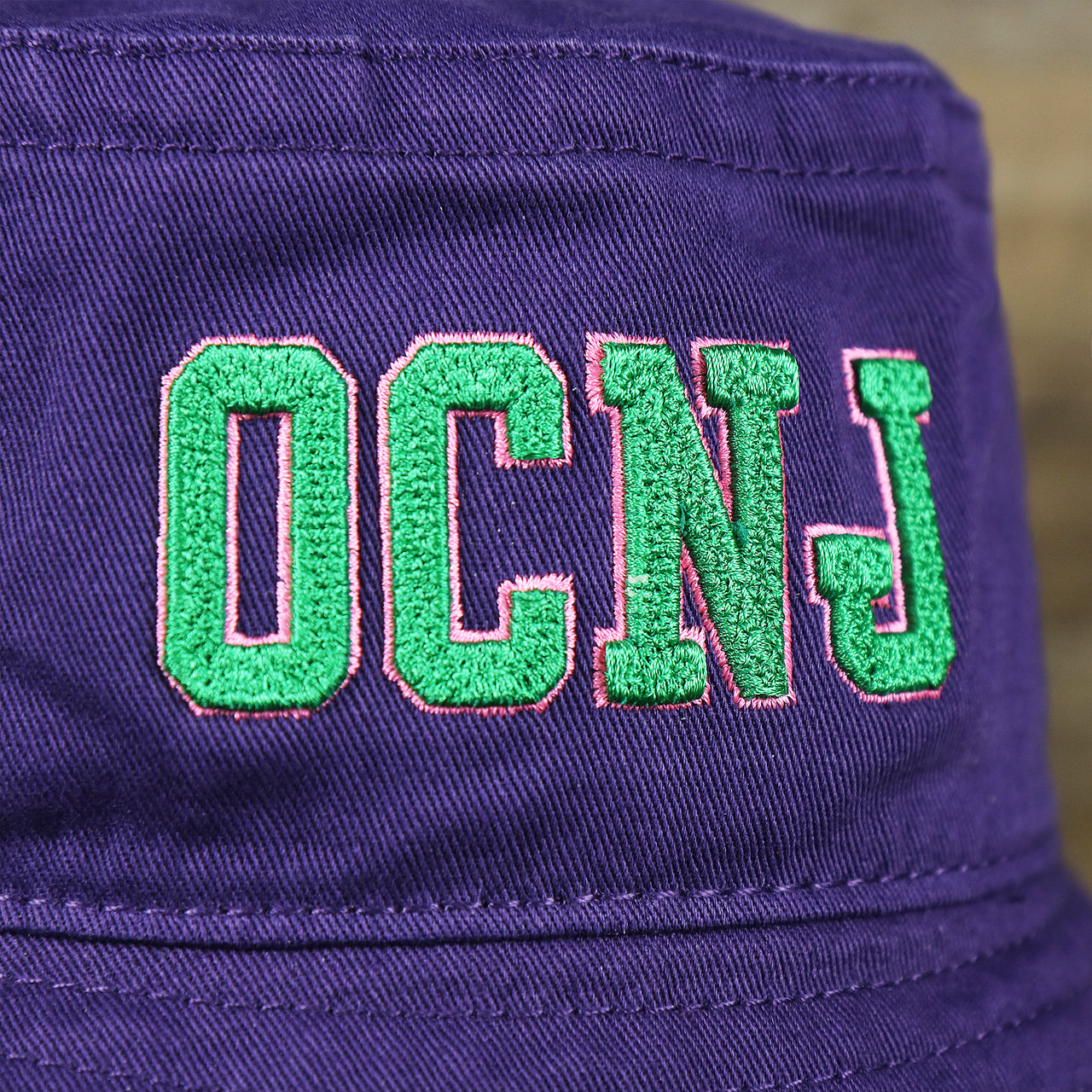The OCNJ Double Wordmark on the Green OCNJ Double Wordmark Pink Outline Bucket Hat | Purple Bucket Hat  
