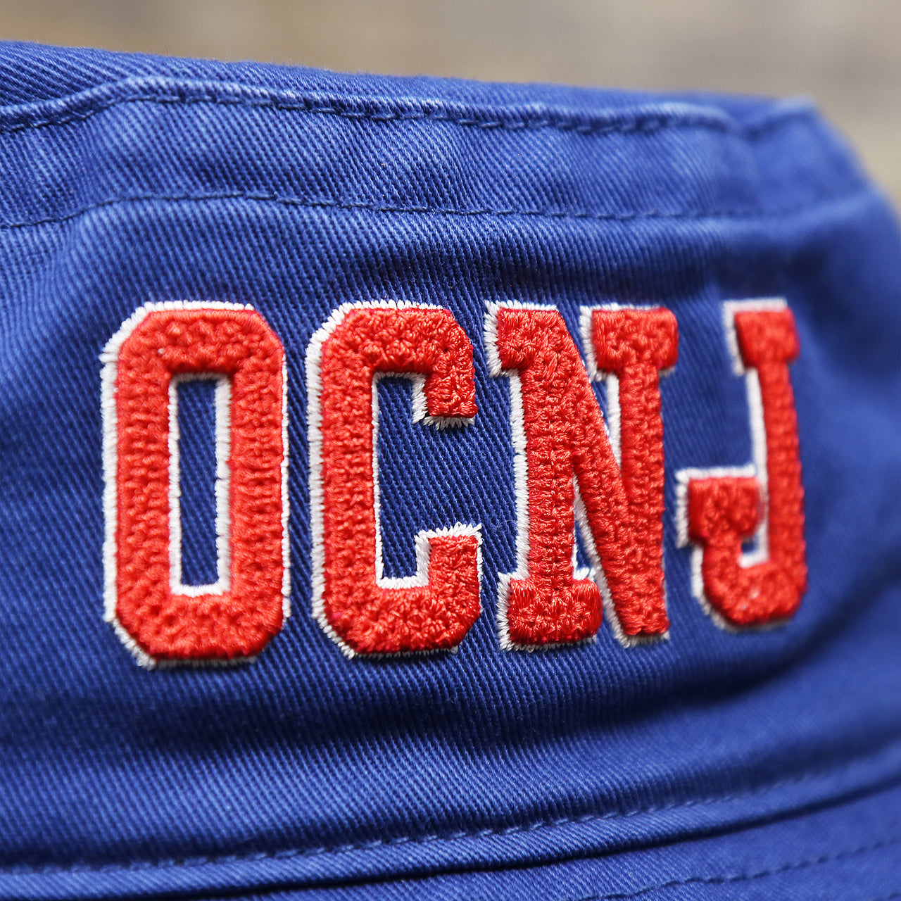 The OCNJ Wordmark on the Ocean City New Jersey OCNJ Wordmark Bucket Hat | Royal Blue Bucket Hat