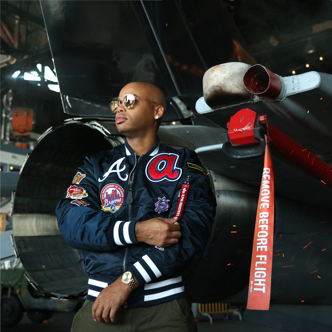 The Atlanta Braves MLB Patch Alpha Industries Reversible Bomber Jacket With Camo Liner | Navy Blue Bomber Jacket in front of a jet