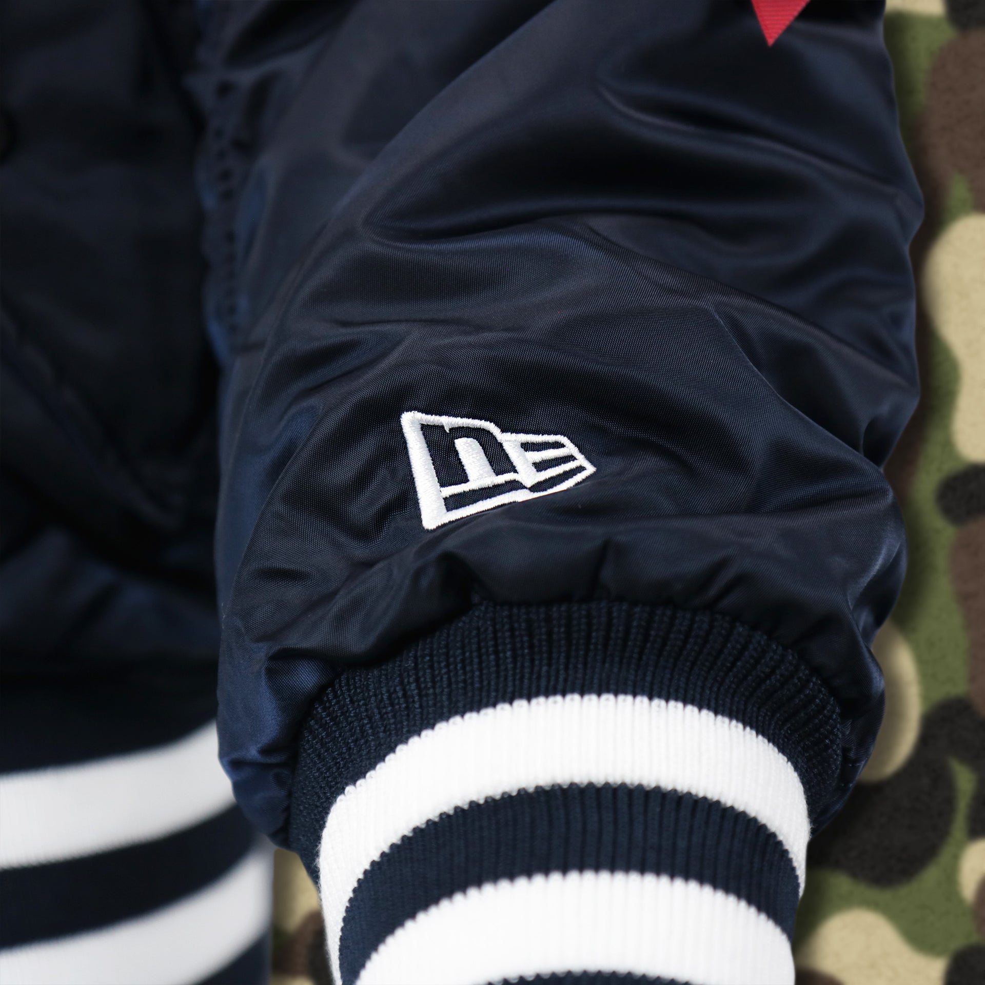The New Era Logo on the Atlanta Braves MLB Patch Alpha Industries Reversible Bomber Jacket With Camo Liner | Navy Blue Bomber Jacket