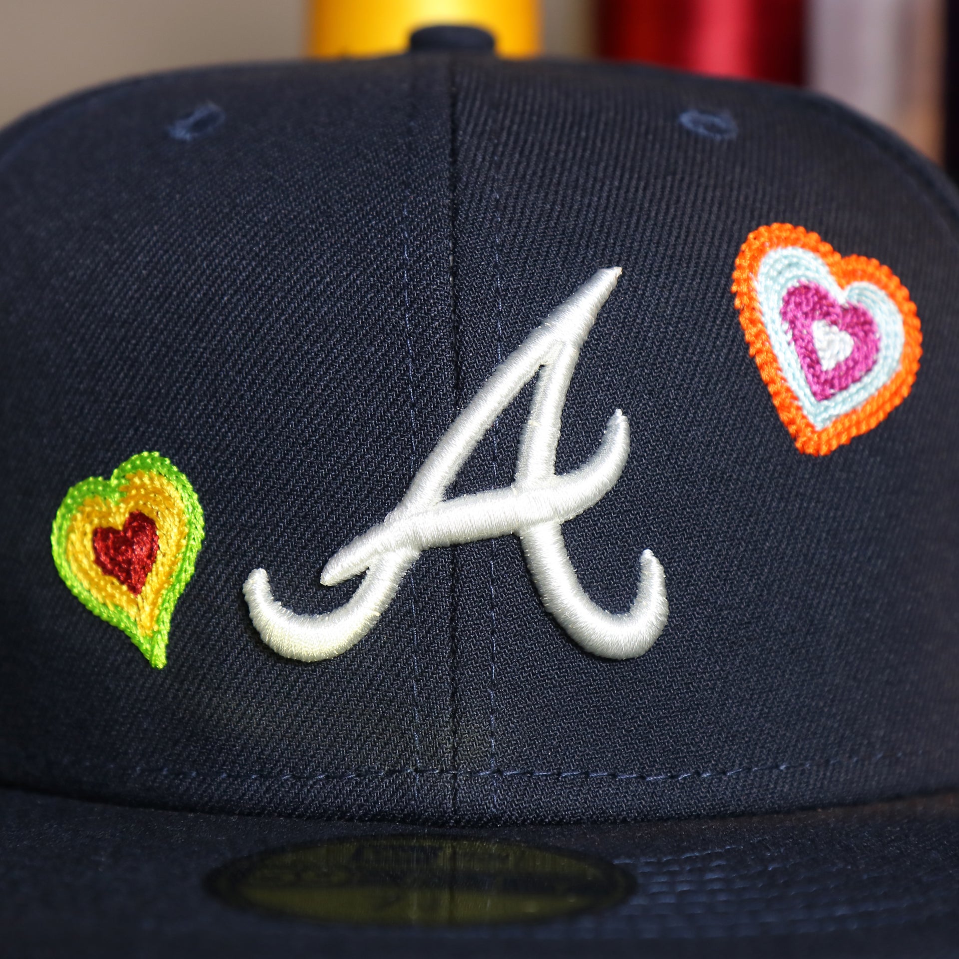 Front close up of the Atlanta Braves All Over Embroidered Chain Stitch Heart Pink Bottom 59Fifty Fitted Cap | Navy 59Fifty Cap