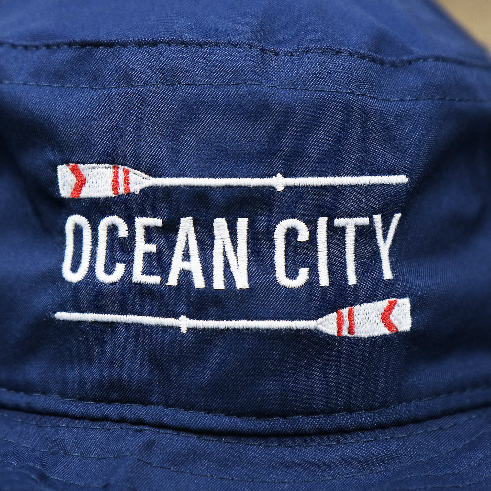 The Ocean City Wordmark on the Ocean City Wordmark Parallel Oars New Jersey Bucket Hat | Navy Blue Bucket Hat