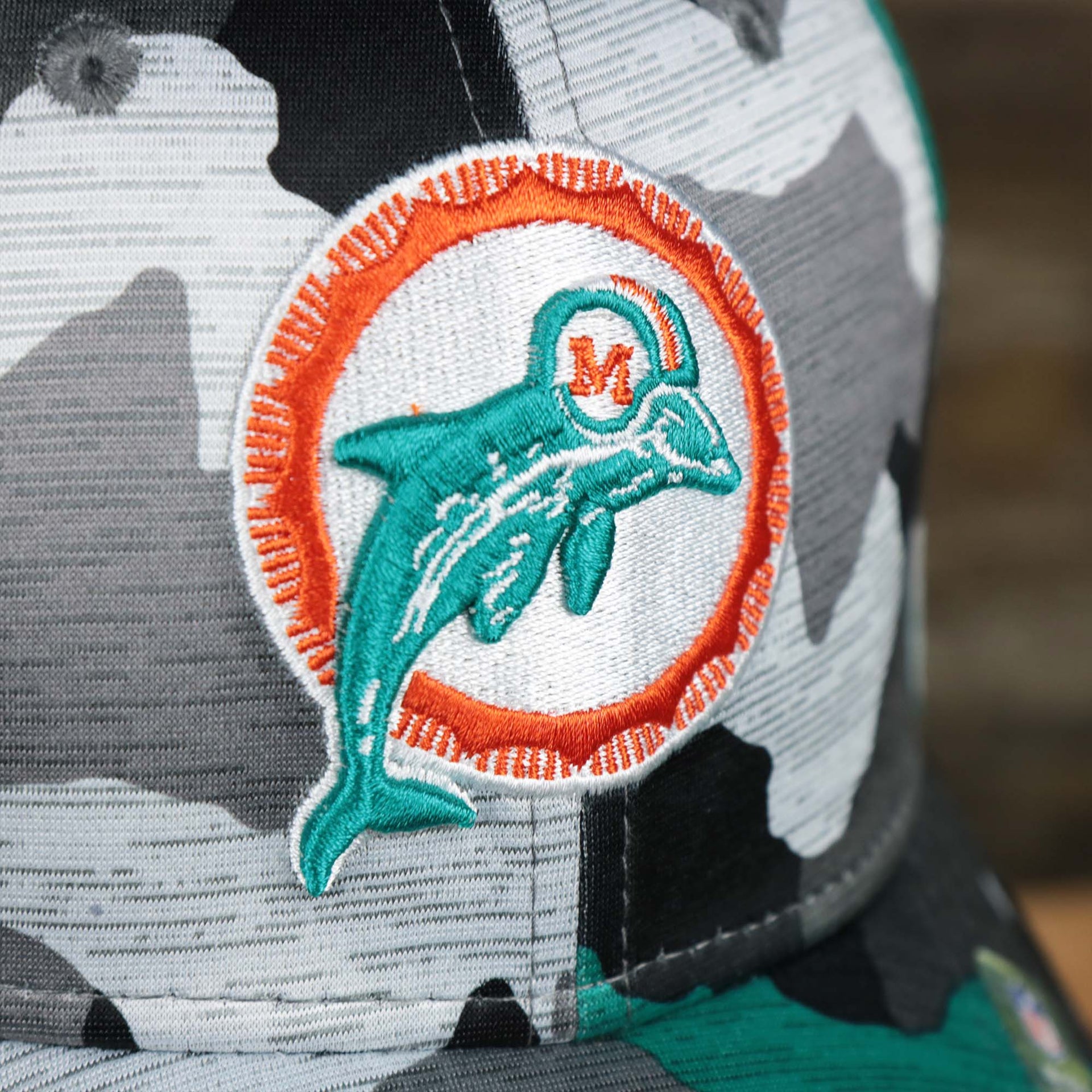 The Dolphins logo on the Throwback Miami Dolphins OnField NFL Summer Training 2022 39Thirty Camo FlexFit Cap | New Era Turquoise