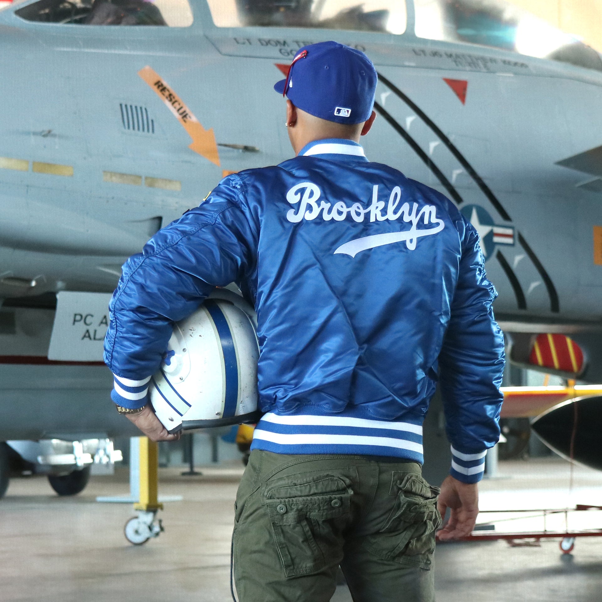 The backside of the Cooperstown Brooklyn Dodgers MLB Patch Alpha Industries Reversible Bomber Jacket With Camo Liner | Royal Blue Bomber Jacket with a matching helmet