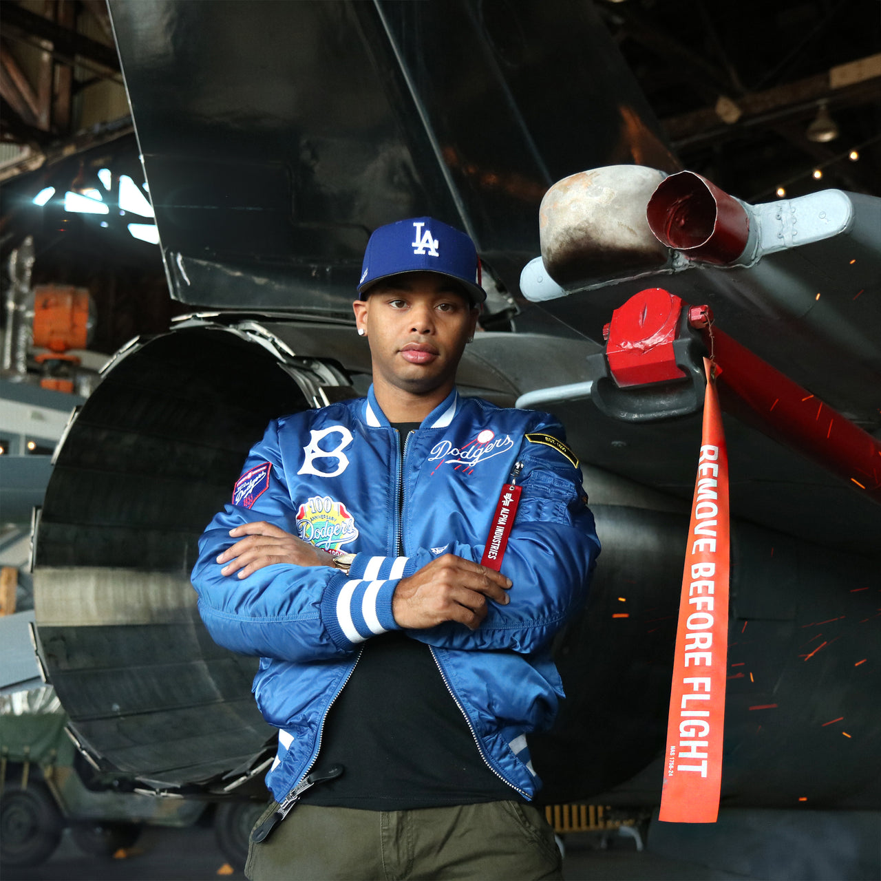 The Cooperstown Brooklyn Dodgers MLB Patch Alpha Industries Reversible Bomber Jacket With Camo Liner | Royal Blue Bomber Jacket in front of a jet