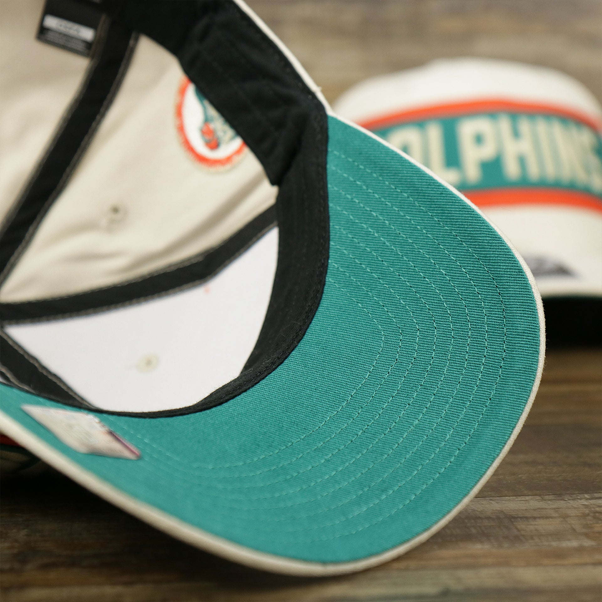 The undervisor on the Throwback Miami Dolphins Striped Wordmark Legacy Dolphins Side Patch Crossroad Dad Hat | Bone Dad Hat