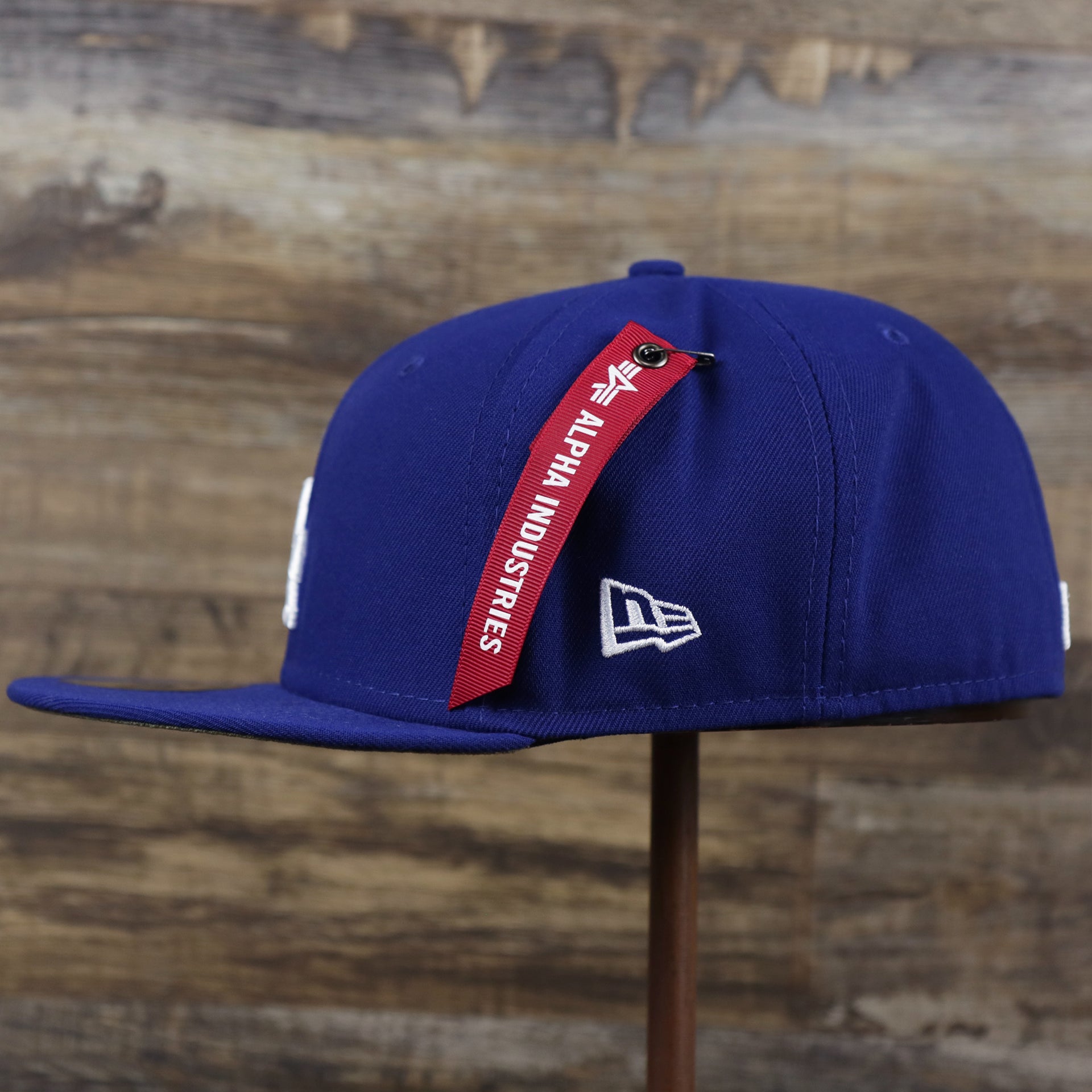 The wearer's left on the Los Angeles Dodgers Alpha Industries Side Patch Army Green Undervisor 59FIfty Fitted Cap With Hangtag | Royal Blue 59FIfty Cap