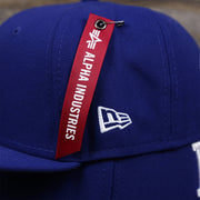 The New Era Logo and the Alpha Hangtag on the Los Angeles Dodgers Alpha Industries Side Patch Army Green Undervisor 59FIfty Fitted Cap With Hangtag | Royal Blue 59FIfty Cap