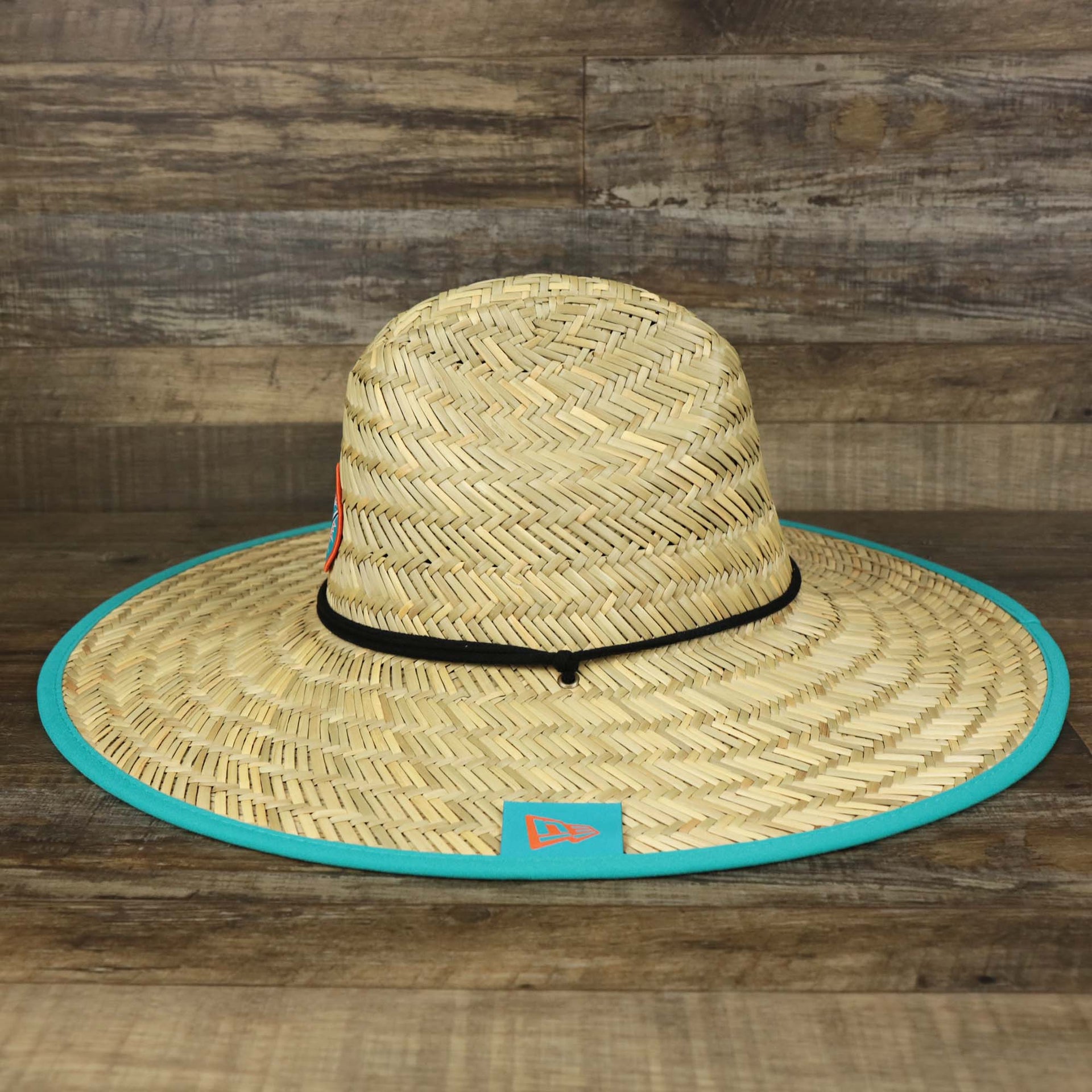 The wearer's left on the Miami Dolphins On Field 2022 Summer Training Straw Hat | New Era OSFM