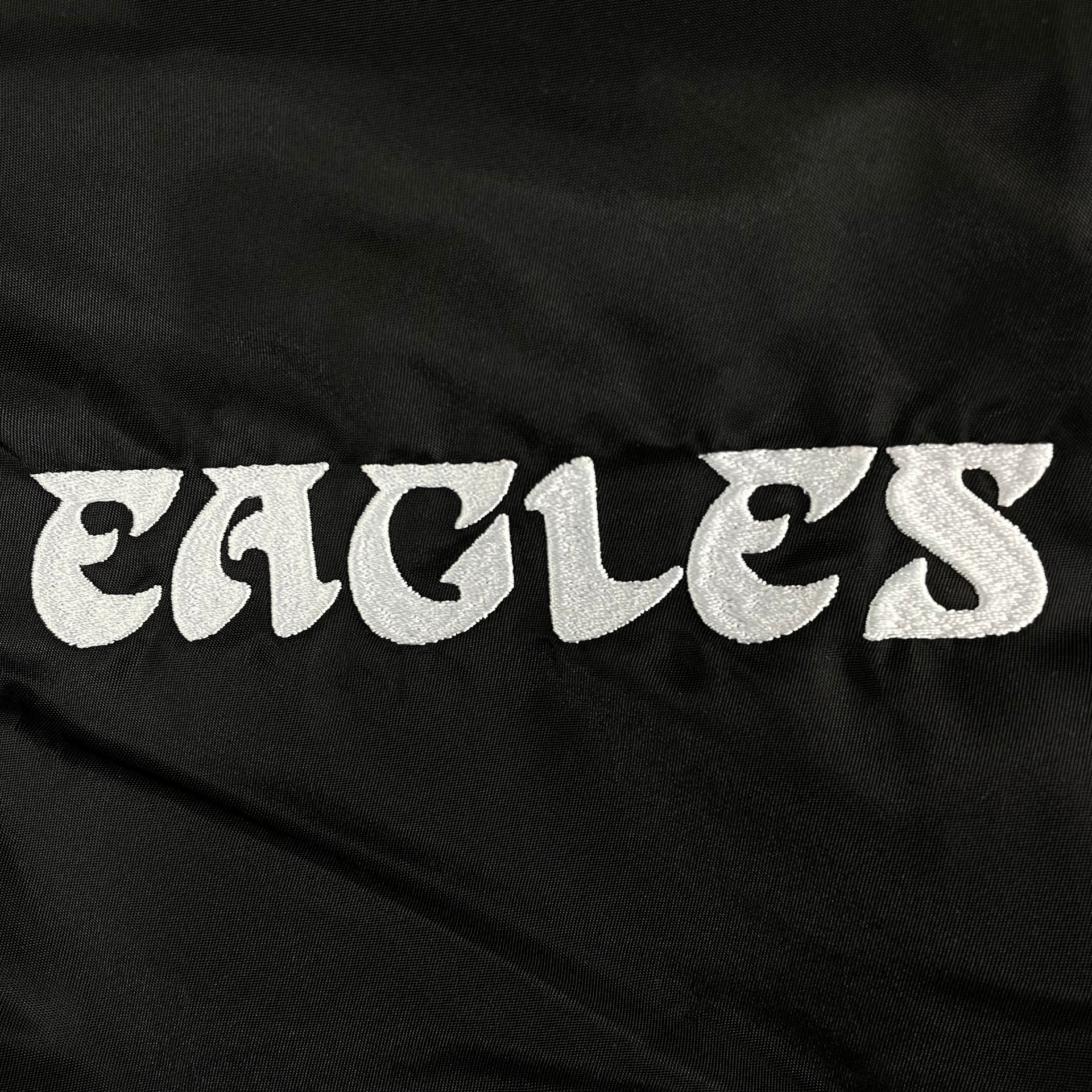 Close up of the retro embroidered wordmark on the Philadelphia Eagles Throwback Men’s Vintage Reversible Bomber Jacket | Alpha Industries x New Era