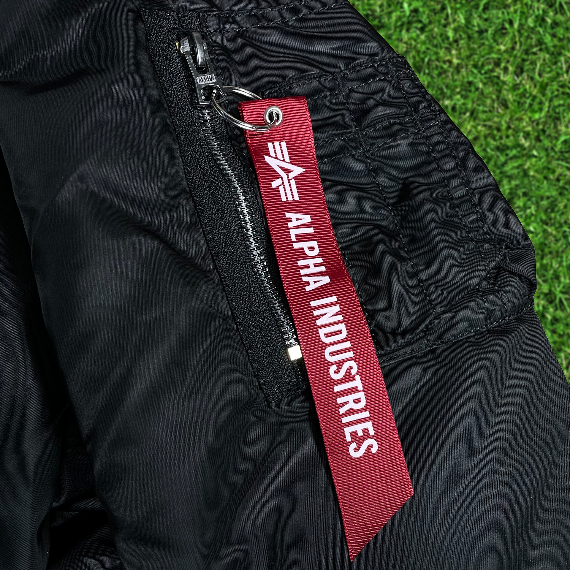 Close up of the Alpha Industries pull-tab on the Philadelphia Eagles Throwback Men’s Vintage Reversible Bomber Jacket | Alpha Industries x New Era