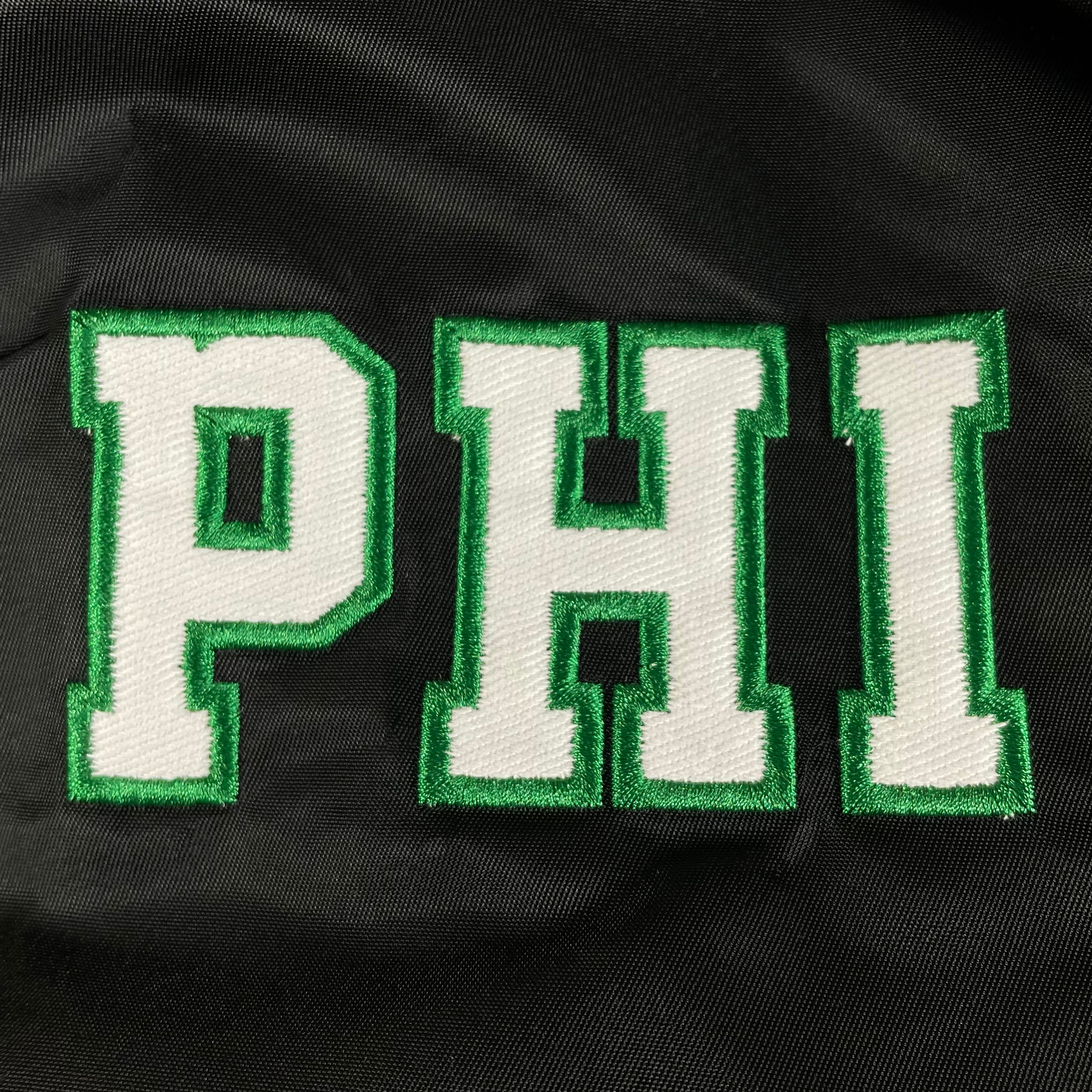 Close up of the lettering patch on the arm of the Philadelphia Eagles Throwback Men’s Vintage Reversible Bomber Jacket | Alpha Industries x New Era