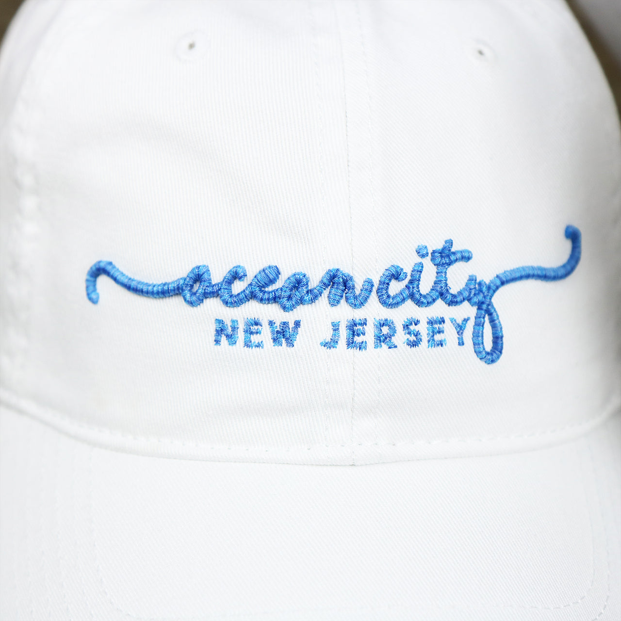The Ocean City New Jersey Wordmark on the OCNJ New Jersey Ocean City Cursive Wordmark Dad Hat | White Dad Hat 