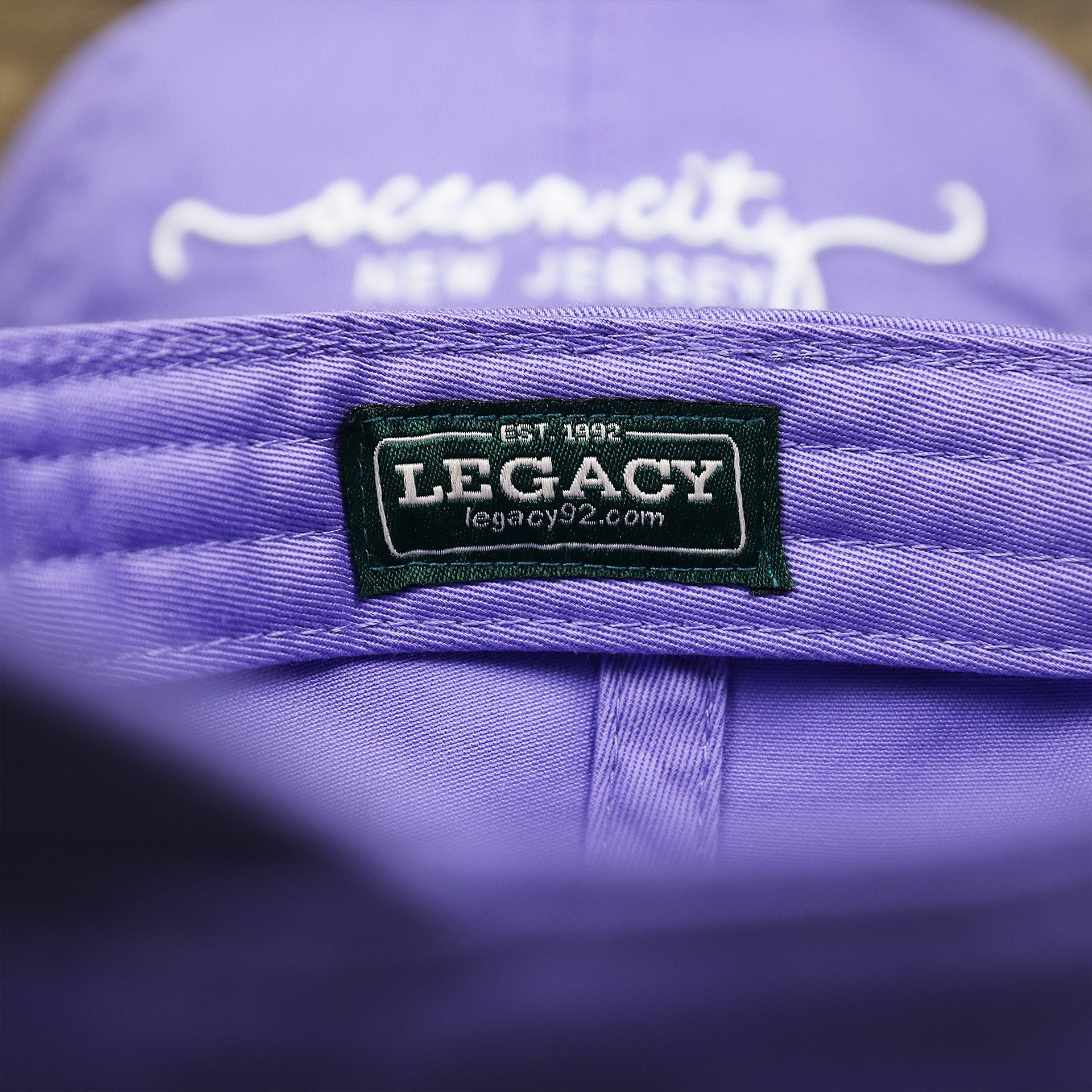 The Legacy Tag on the Ocean City New Jersey Cursive Wordmark Dad Hat | Lavender Dad Hat