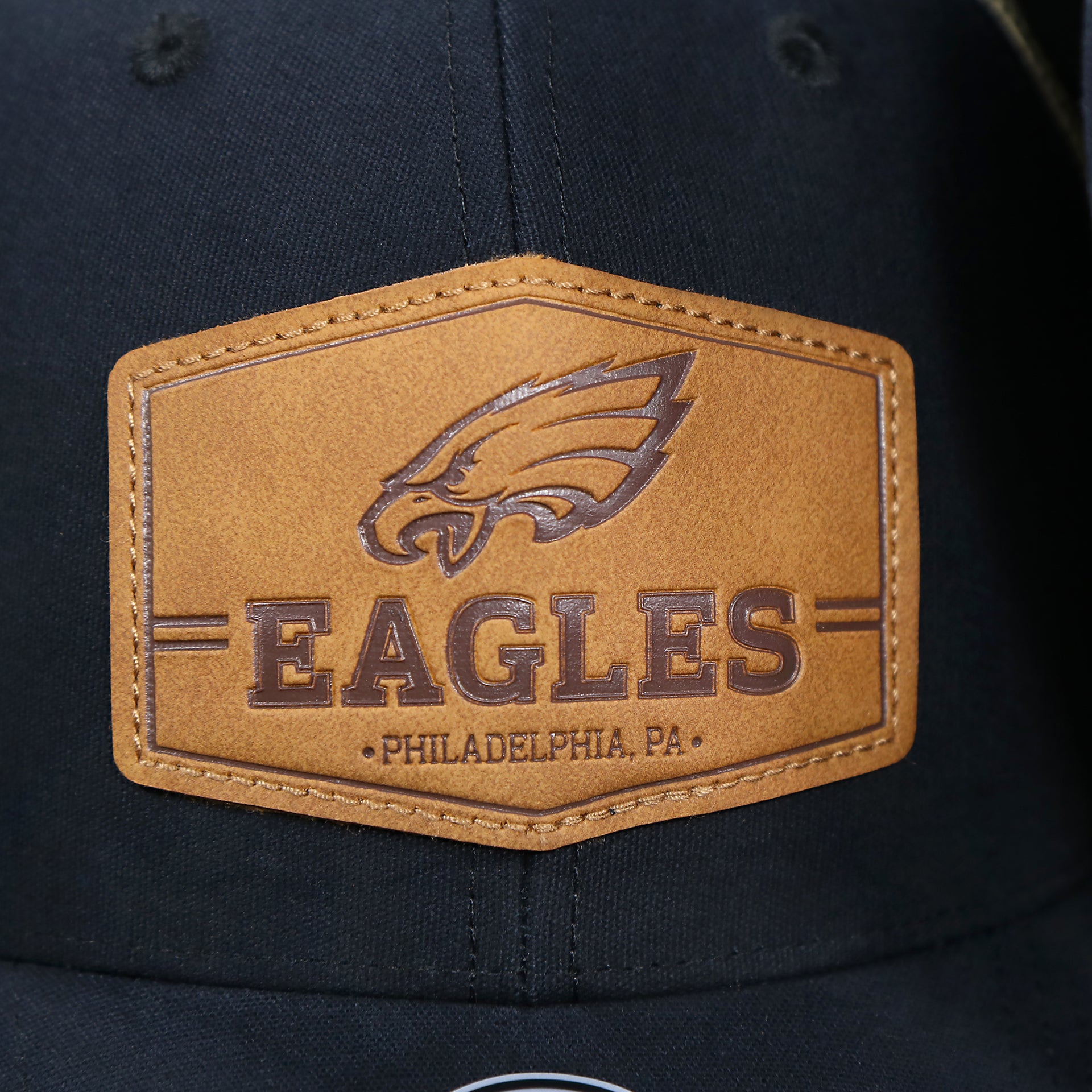 The Eagles Leather Patch on the Philadelphia Eagles Leather Patch Mesh Back Trucker Hat | Black Trucker Hat