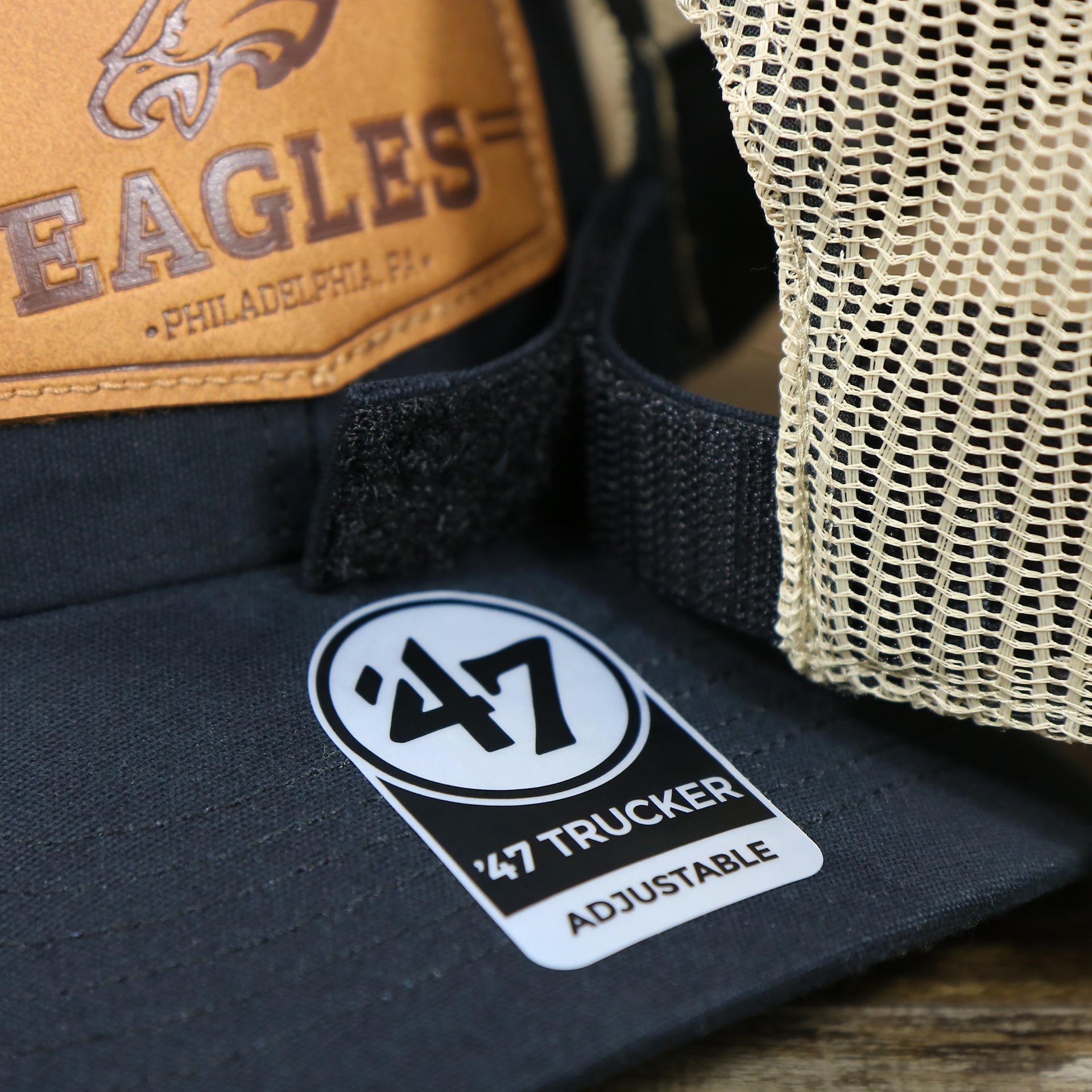 The 47 brand Sticker on the Philadelphia Eagles Leather Patch Mesh Back Trucker Hat | Black Trucker Hat