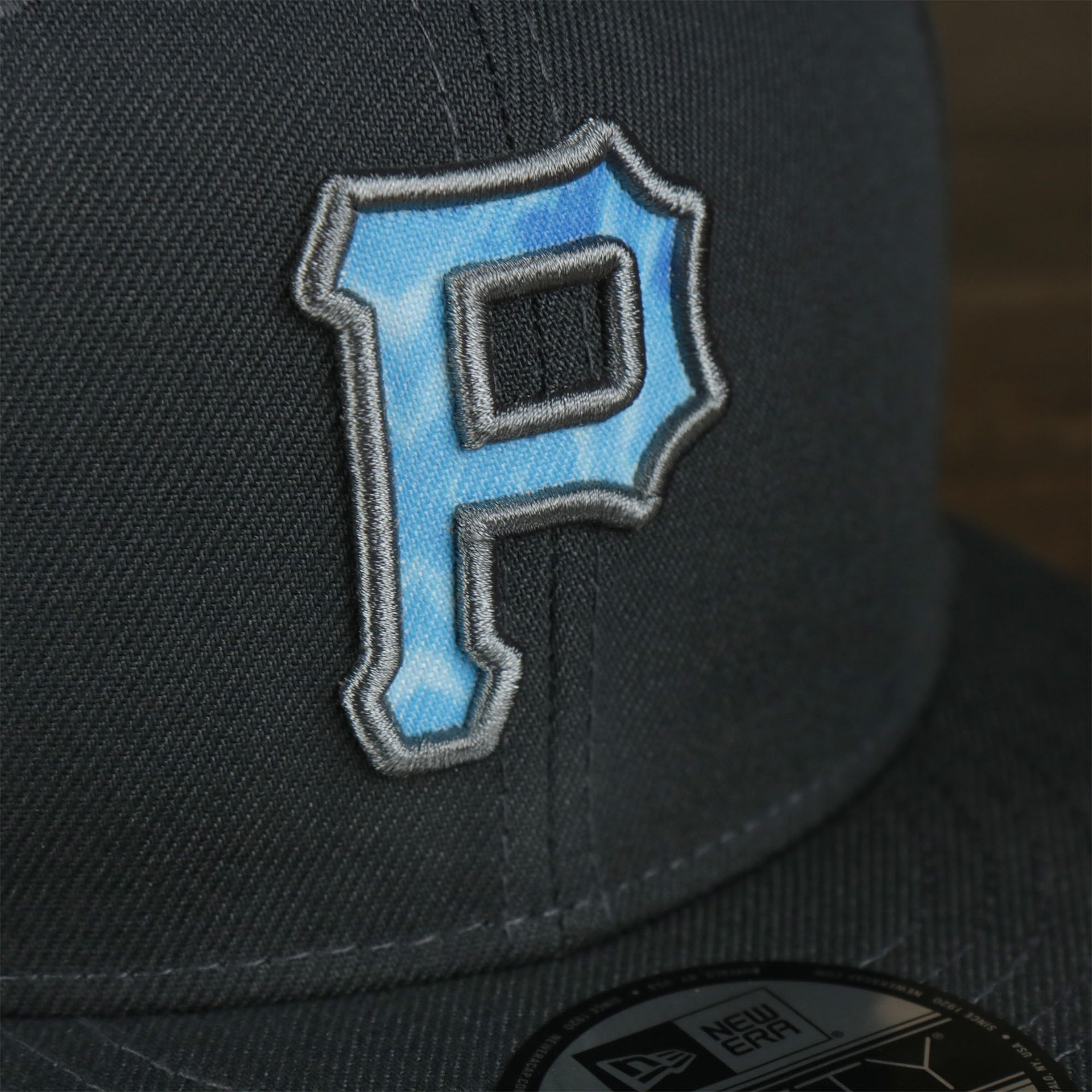 A close up of the logo on the Pittsburgh Pirates 2022 Father's Day On-Field 9Fifty Snapback | Gray