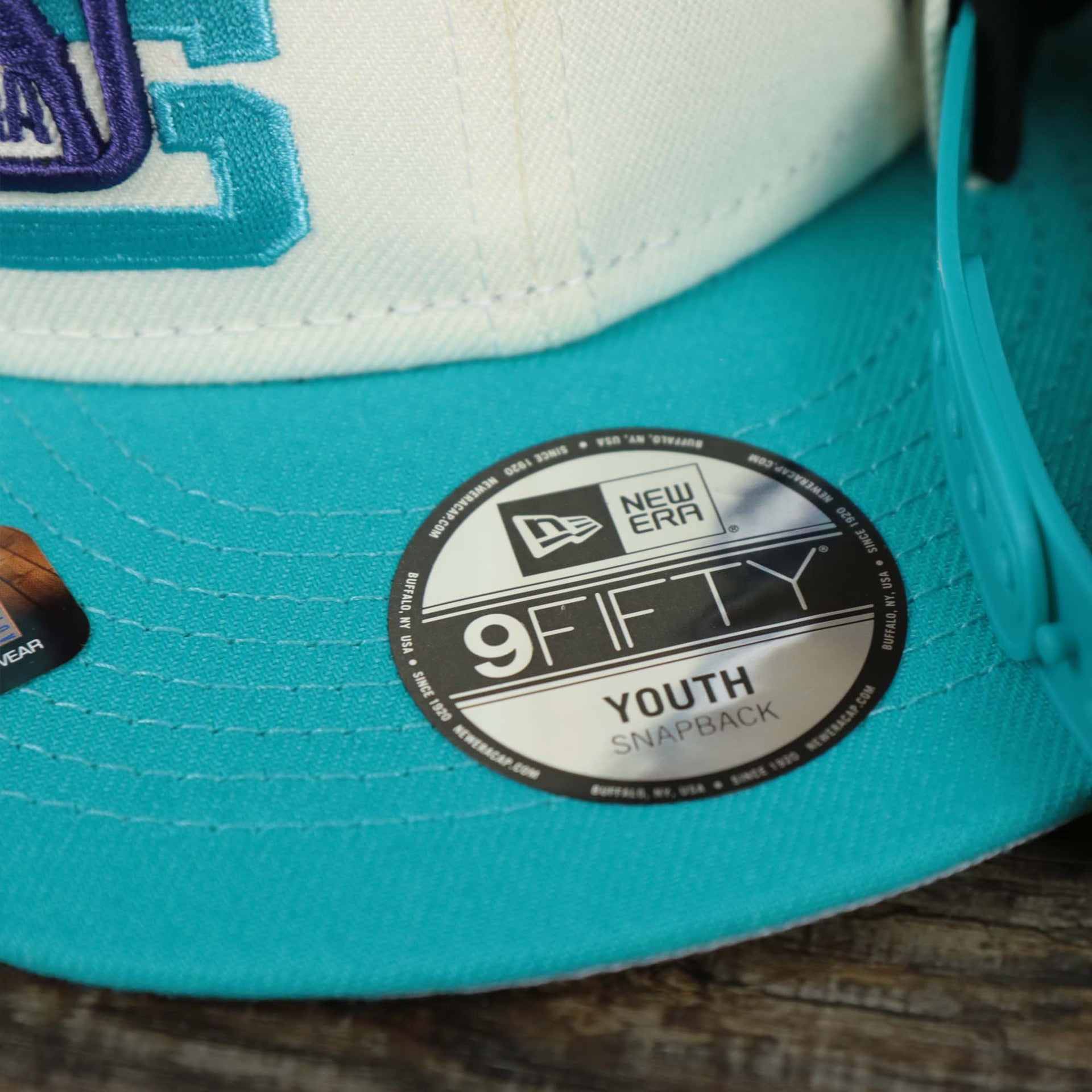 The 9Fifty Sticker on the Youth Charlotte Hornets NBA 2022 Draft Gray Bottom 9Fifty Snapback | New Era Cream/Turquoise