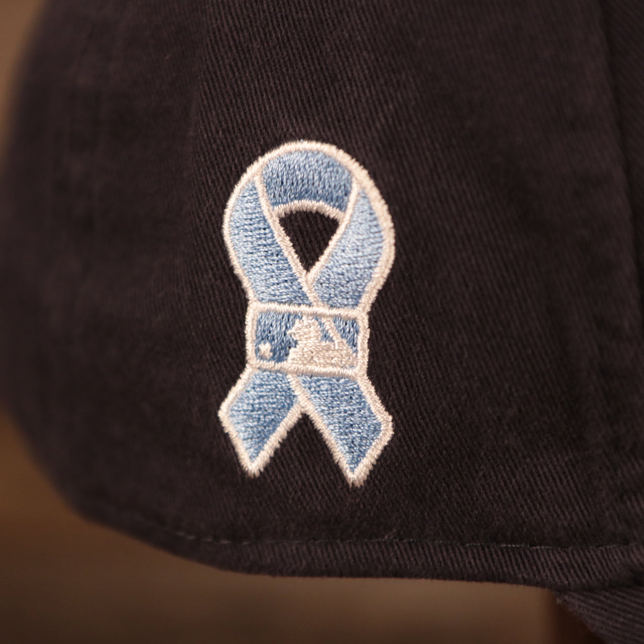 A close up of the light blue ribbon patch on the wearer's right side of the New York Yankees navy blue fathers day 2021 920 cap by New Era.