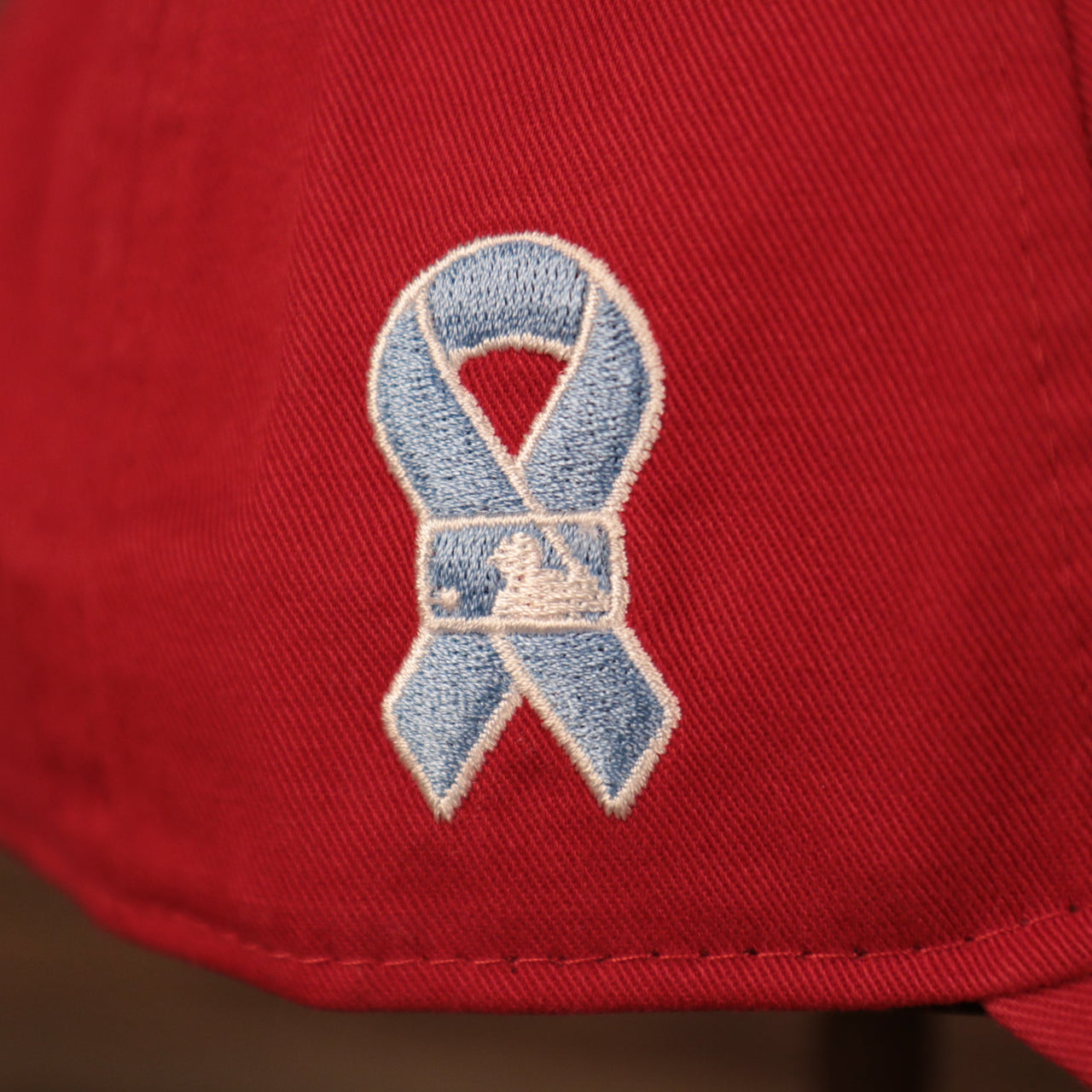 A close up shot of the light blue ribbon patch on the wearer's right side of the red Fightin' Phils fathers day 2021 920 cap by New Era.