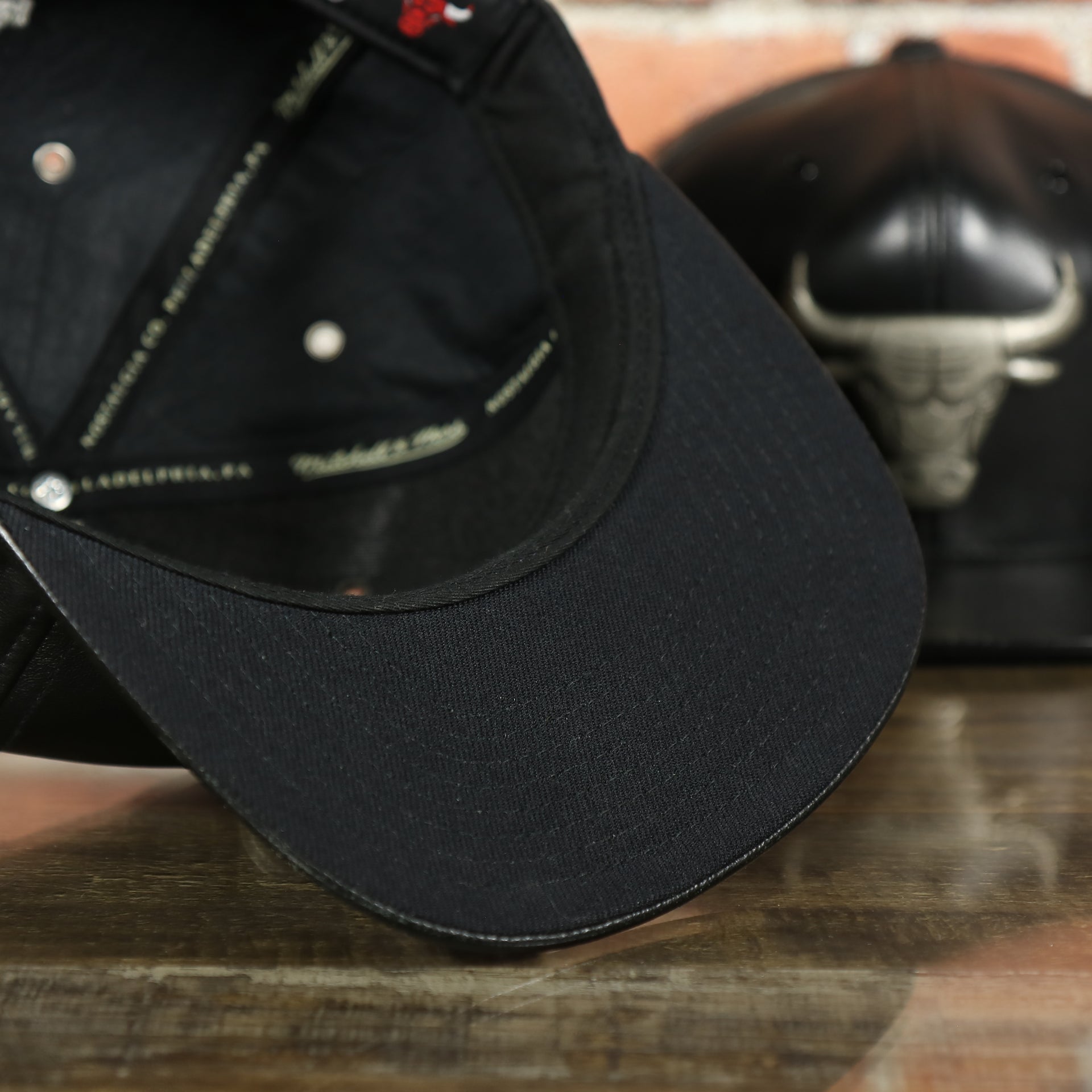 black under visor on the Chicago Bulls 100% Genuine Lambskin Leather Metallic Embossed Bull Logo Mitchell and Ness Black Snapback Hat
