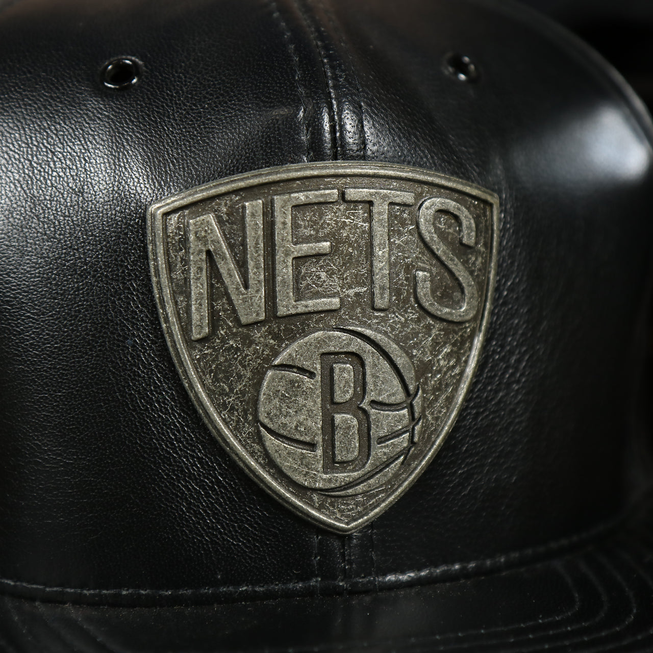 nets logo on the Brooklyn Nets 100% Genuine Lambskin Leather Mitchell and Ness Embossed Metalic Shield Snapback Hat