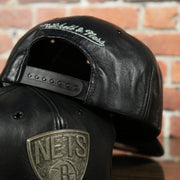 black adjustable snap on the Brooklyn Nets 100% Genuine Lambskin Leather Mitchell and Ness Embossed Metalic Shield Snapback Hat