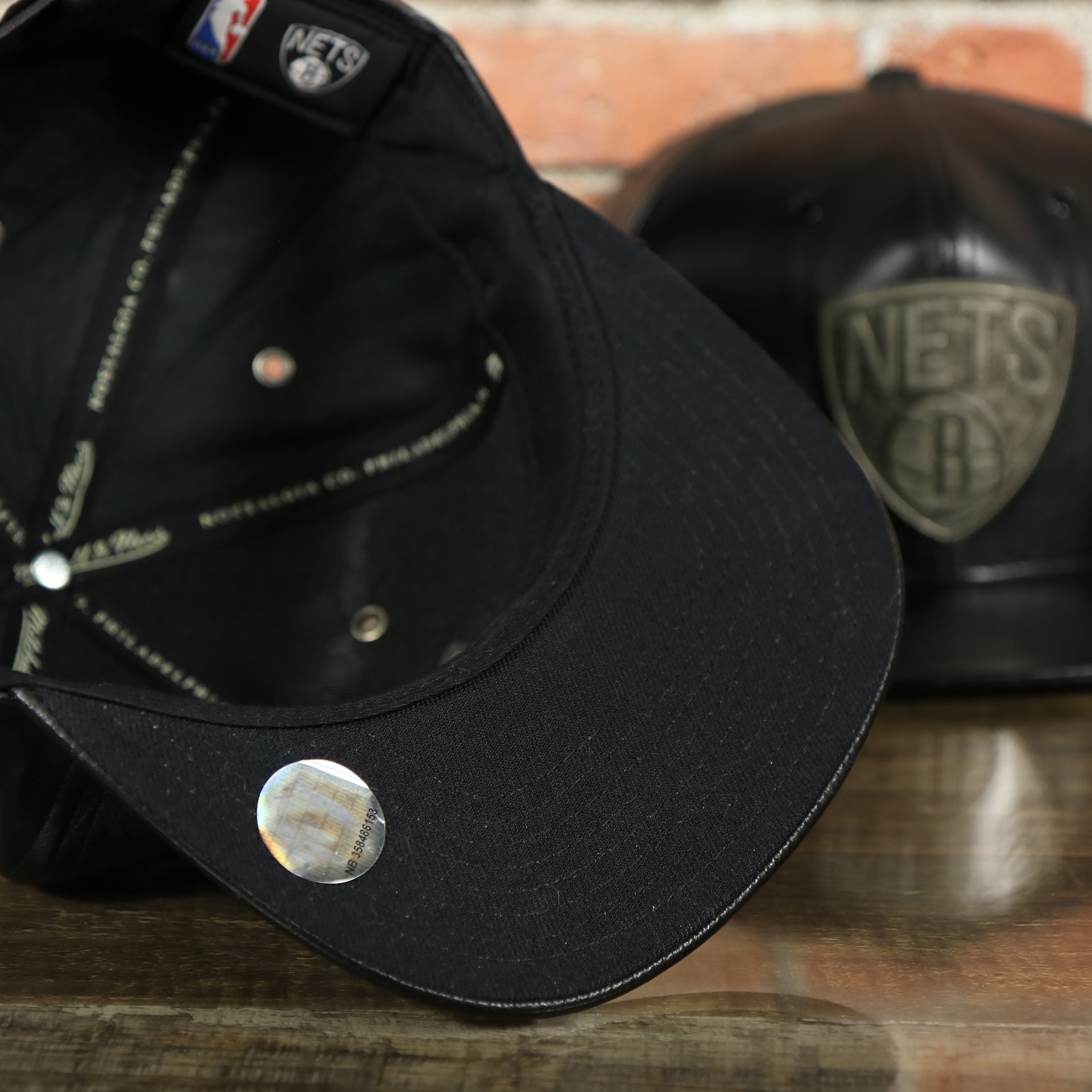 black under visor on the Brooklyn Nets 100% Genuine Lambskin Leather Mitchell and Ness Embossed Metalic Shield Snapback Hat