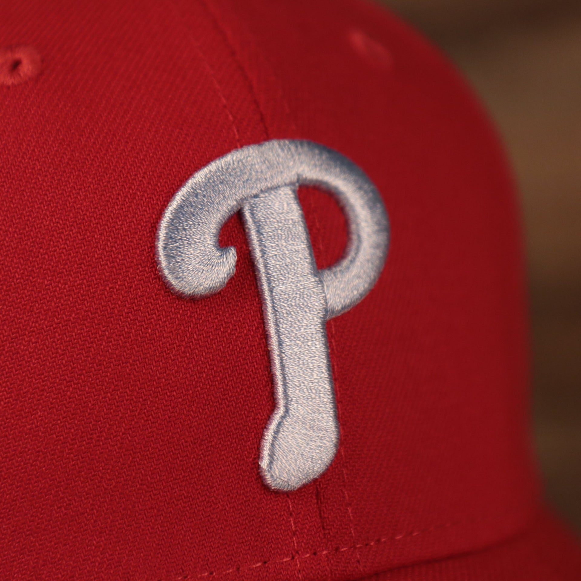 A close up of the light blue Phillies logo patch on the front side of the red fathers day 2021 MLB 39thirty flexfit cap by New Era.