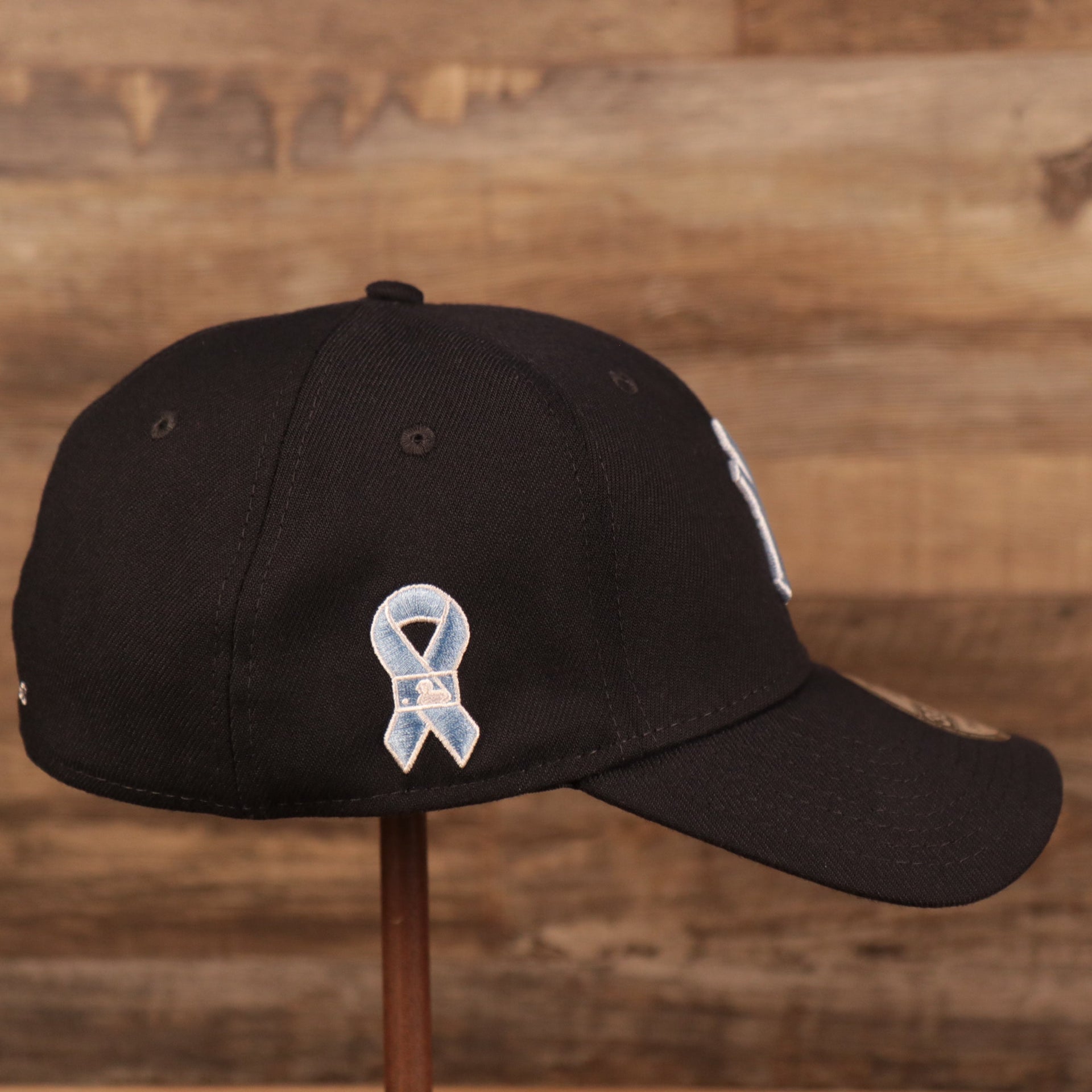 The light blue ribbon patch on the wearer's right side of the New York Yankees navy blue fathers day 2021 39Thirty flexfit cap by New Era.