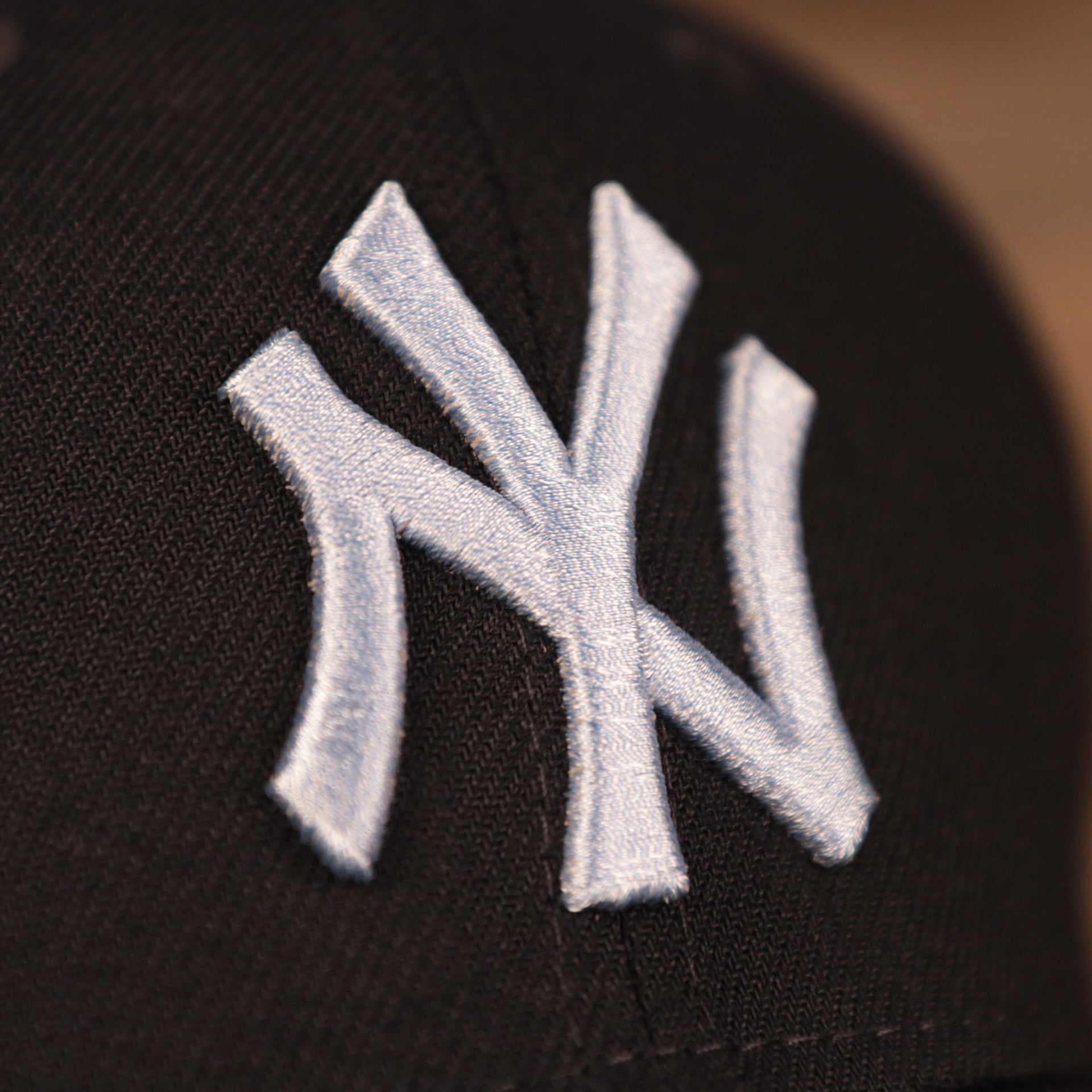 A close up of the light blue Yankees logo patch on the front side of the navy blue fathers day 2021 MLB 39thirty flexfit cap by New Era.