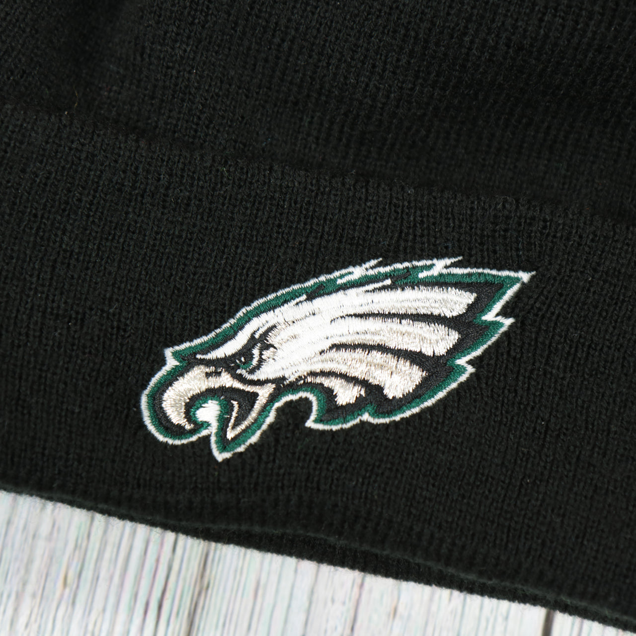 eagles logo on the Philadelphia Eagles Super Bowl LII Patch Pom Pom Beanie | Midnight Green, Black, And White Striped Beanie