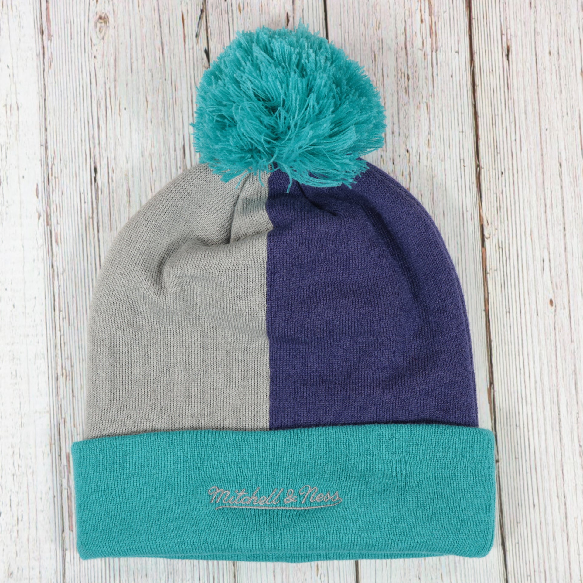 back side of the Charlotte Hornets Cuffed Logo Split Beanie With Black Pom Pom | Teal, White, And Black Beanie