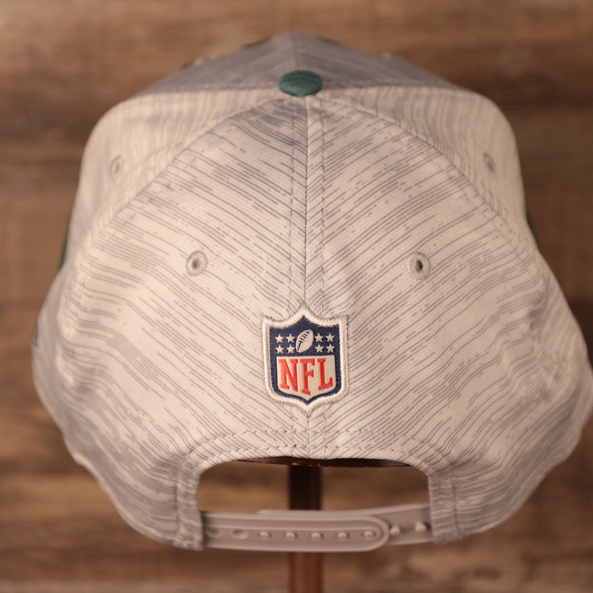 The NFL logo on the back of gray New Era nfl on field training snapback hat.