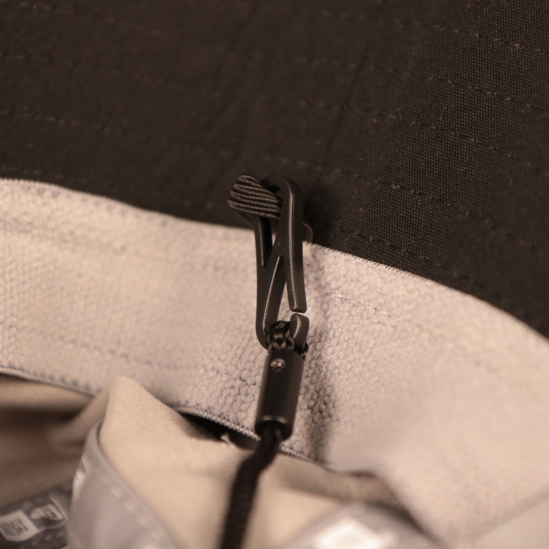A closeup shot of the adjustable strings of the gray nfl on field training bucket hat carolina panthers by New Era.