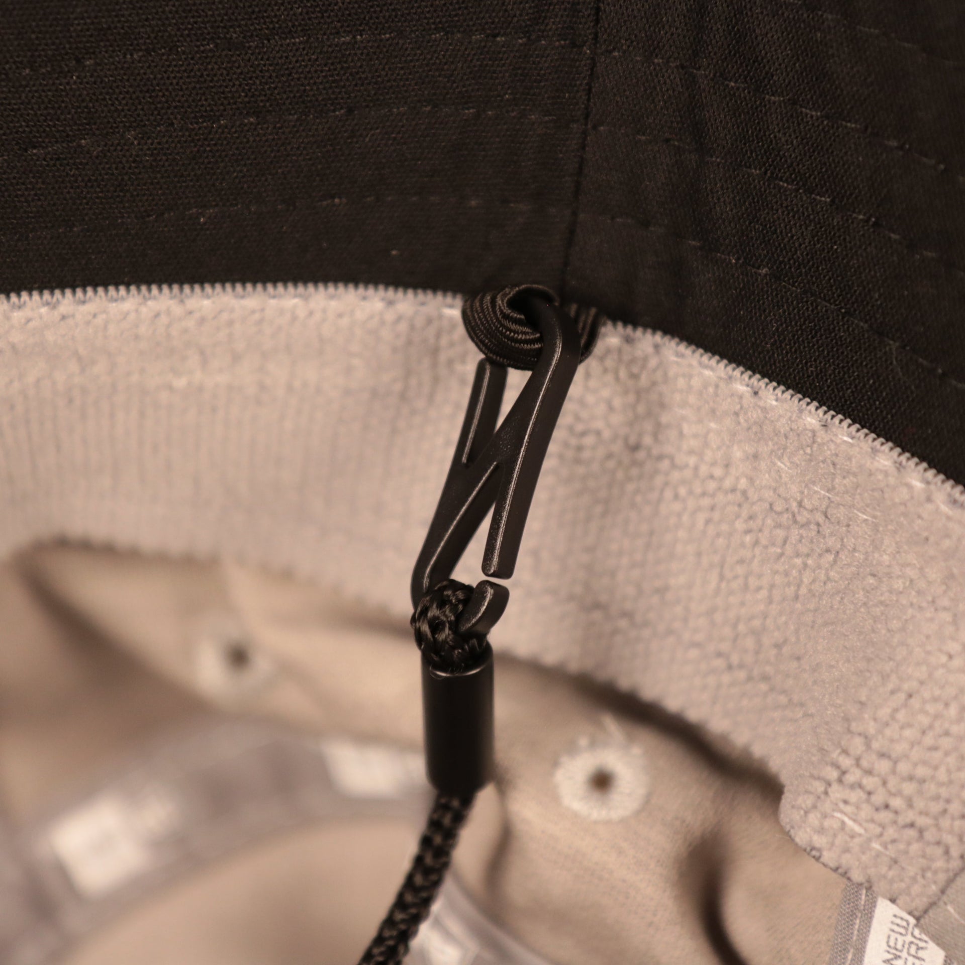 A closeup shot of the adjustable strings of the gray nfl on field training bucket hat by New Era.