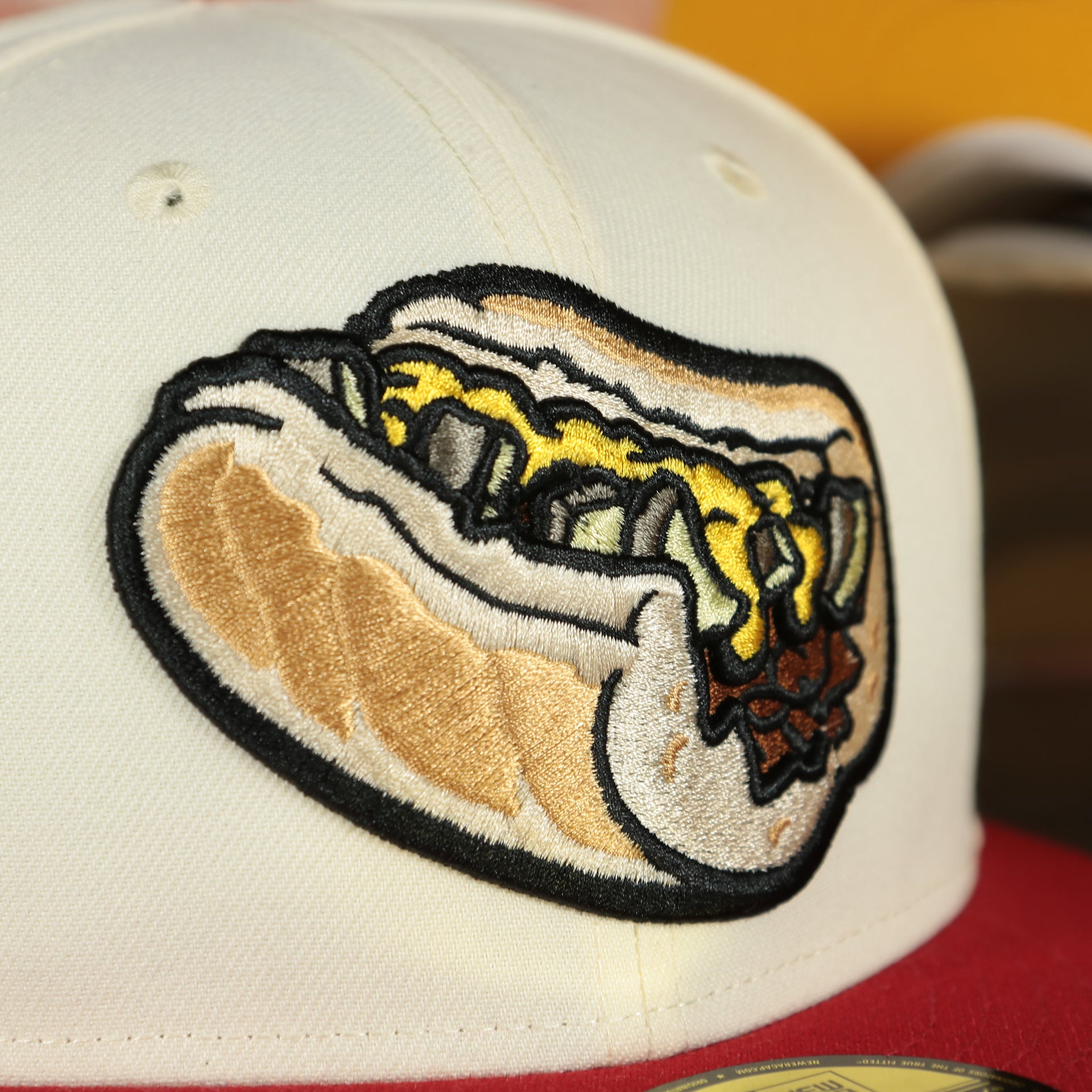 Close up of the front logo on the Lehigh Valley Iron Pigs Cheesesteak With Onions Yellow UV Plain Jane 59Fifty Fitted Cap | Cap Swag Exclusive