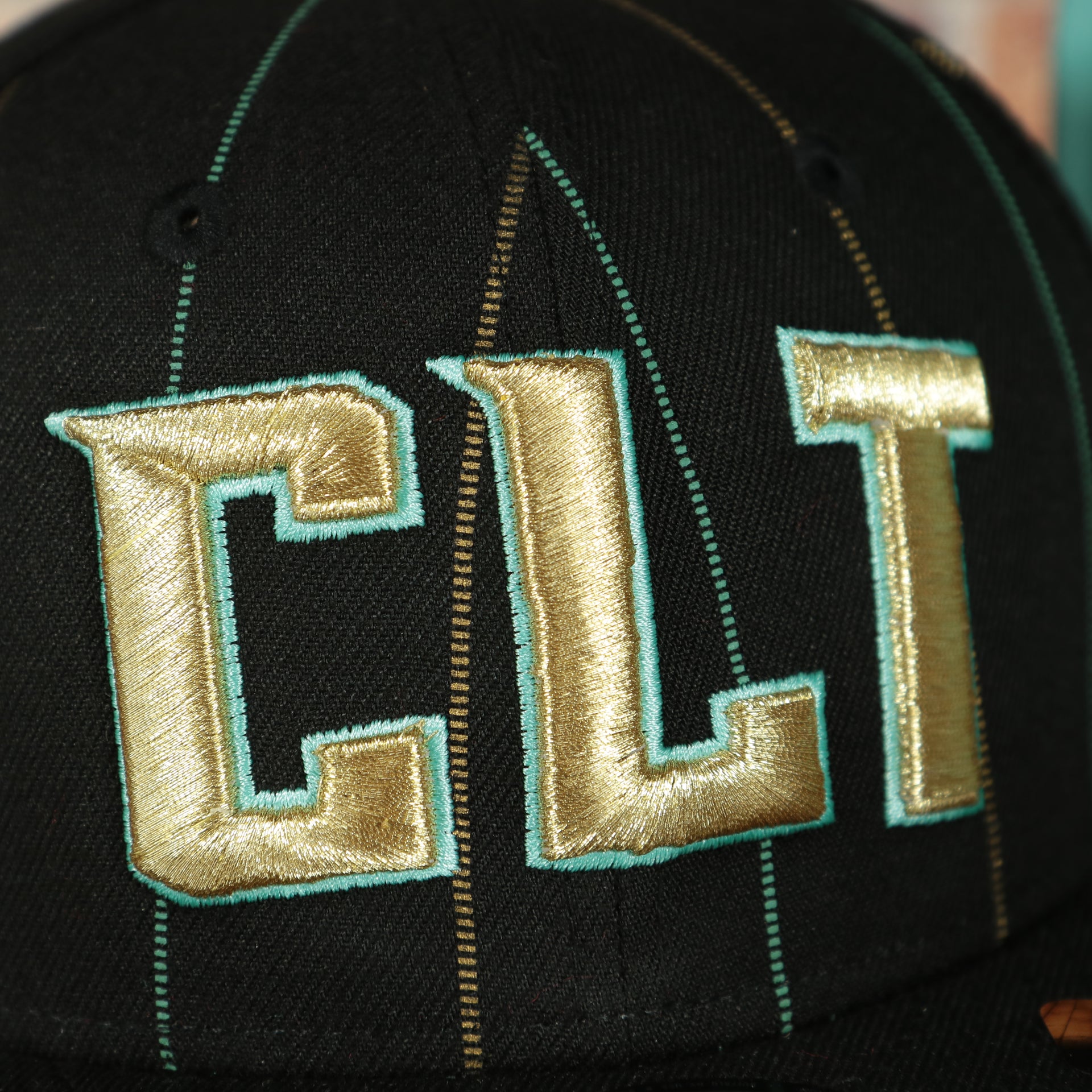 CLT logo on the front side of the Charlotte Hornets 2022 City Edition CLT Logo Teal Bottom Youth 9Fifty Side Patch Snapback Cap | New Era, Black