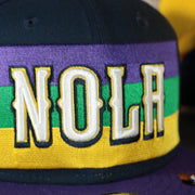 NOLA city edition logo on the front of the New Orleans Pelicans 2022 City Edition NOLA Logo Yellow Bottom Youth 9Fifty Side Patch Snapback Cap | New Era, Navy