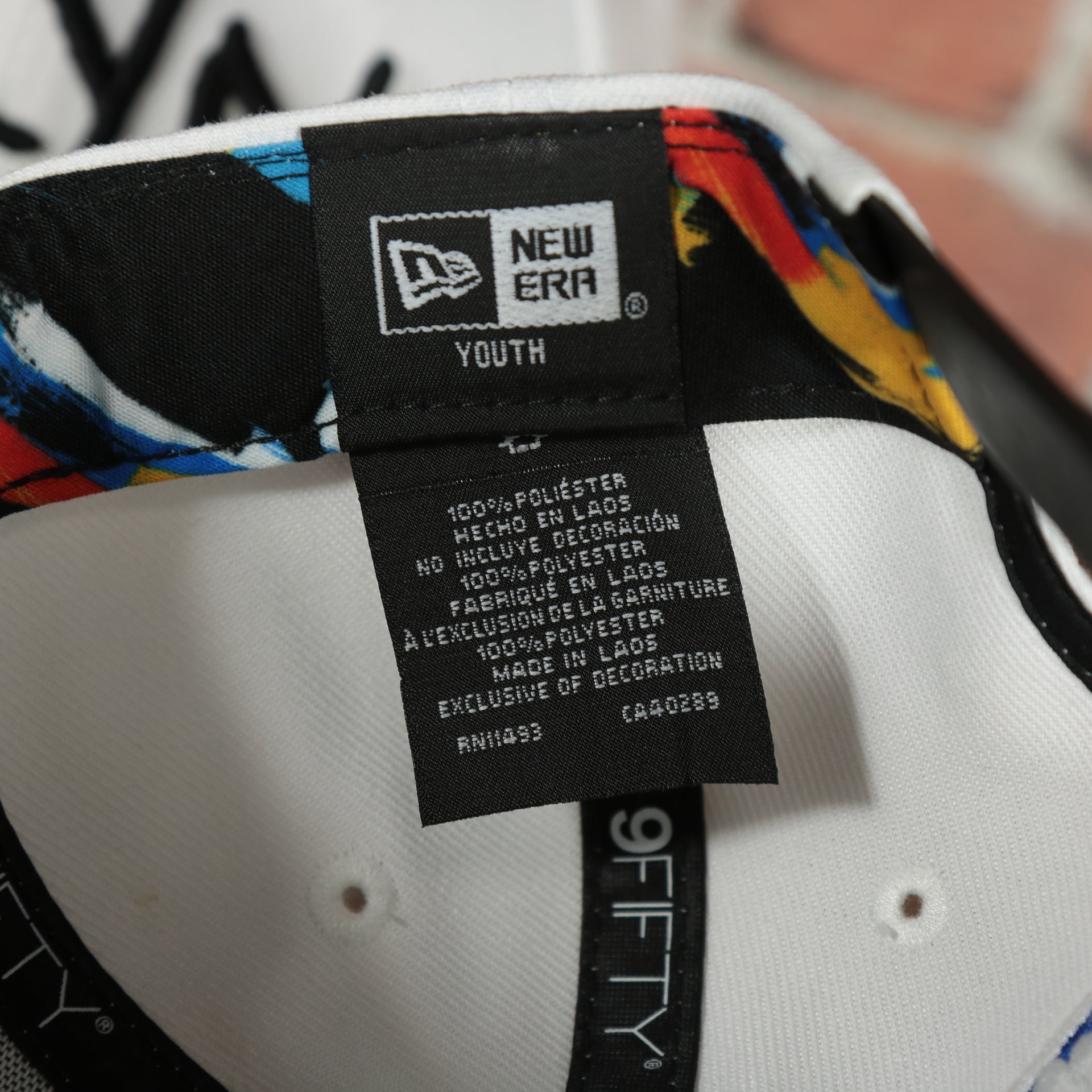 youth tag on the inside of the Brooklyn Nets 2022 City Edition BKLYN Nets Scribble Logo Multi-Color Bottom Youth 9Fifty Side Patch Snapback Cap | New Era, White