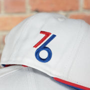 vintage 76ers logo on the wearers right side of the Philadelphia 76ers 2022 City Edition City Of Brotherly Love Blue Bottom Youth 9Fifty Side Patch Snapback Cap | New Era, White