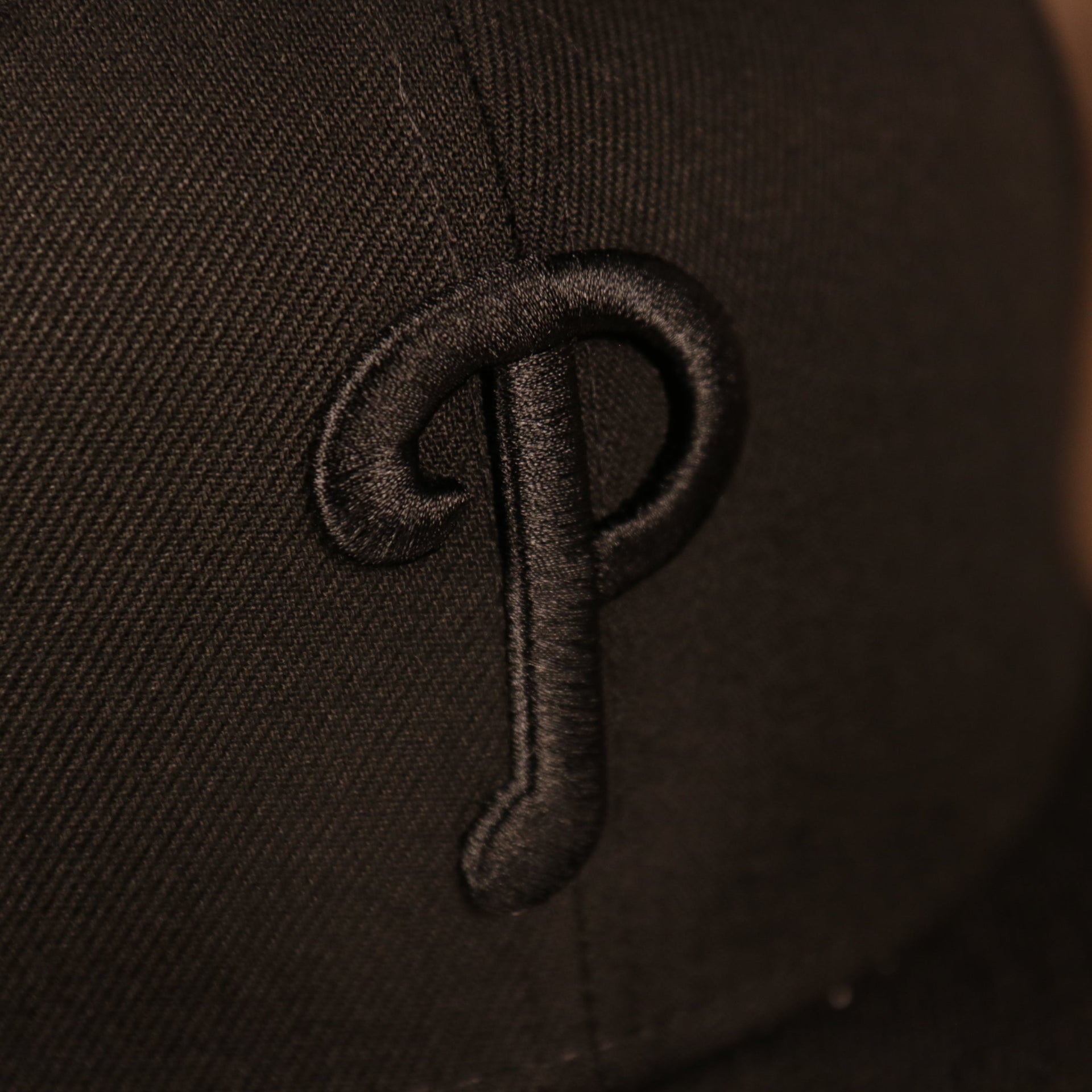 Close up of the Philadelphia Phillies logo on the front of the Philadelphia Phillies Black on Black Tonal Grey Bottom 9Fifty Snapback Hat