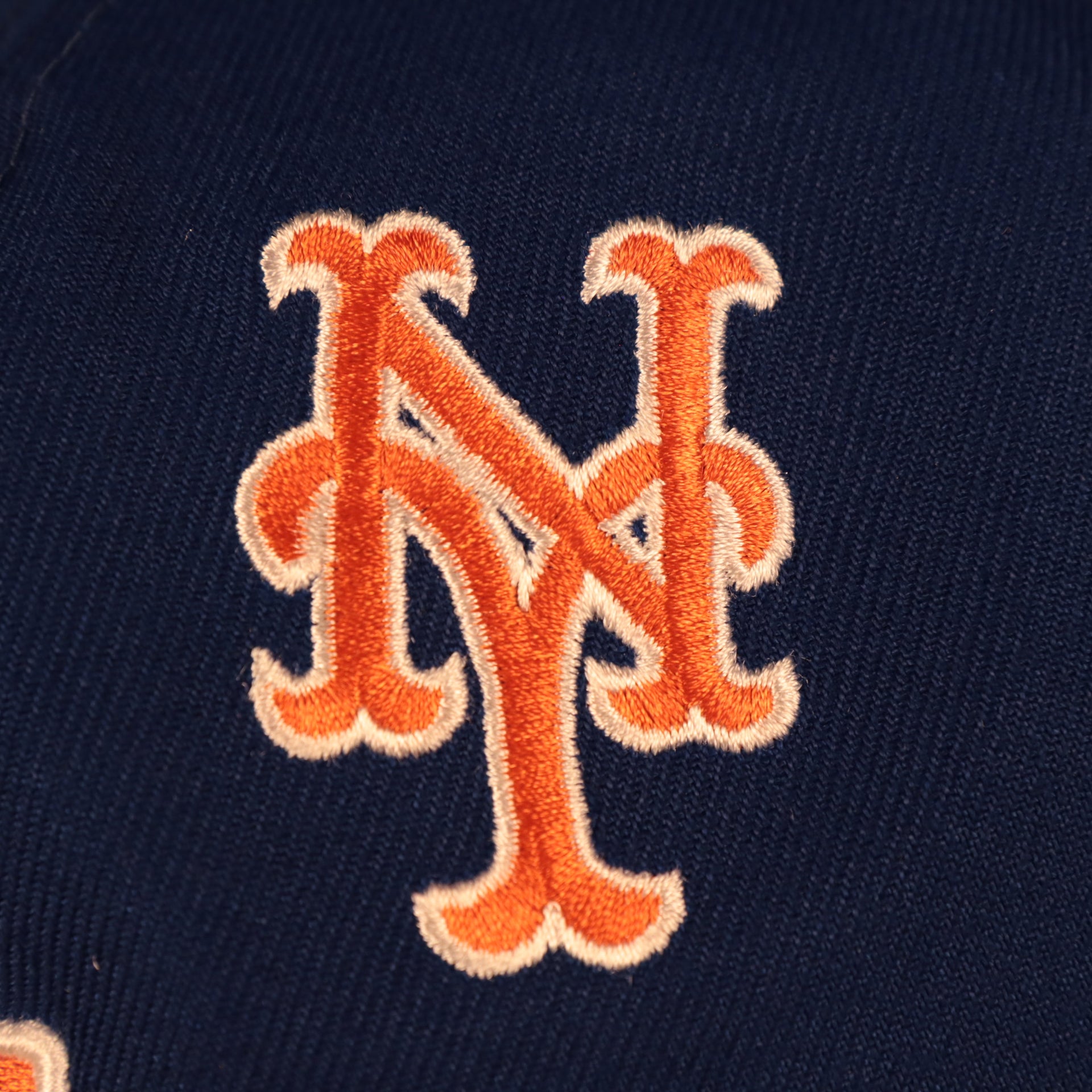 Close up of the alternate New York Mets logo on the back of the New York Mets "Patch Pride" All Over Gray Bottom Side Patch 59Fifty Fitted Cap