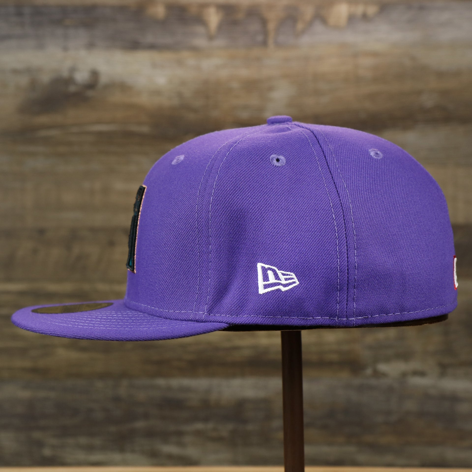 The wearer's left of the Cooperstown Arizona Diamondbacks Gray Bottom Bloom Spring Embroidery 59Fifty Fitted Cap | Purple 59Fifty Cap