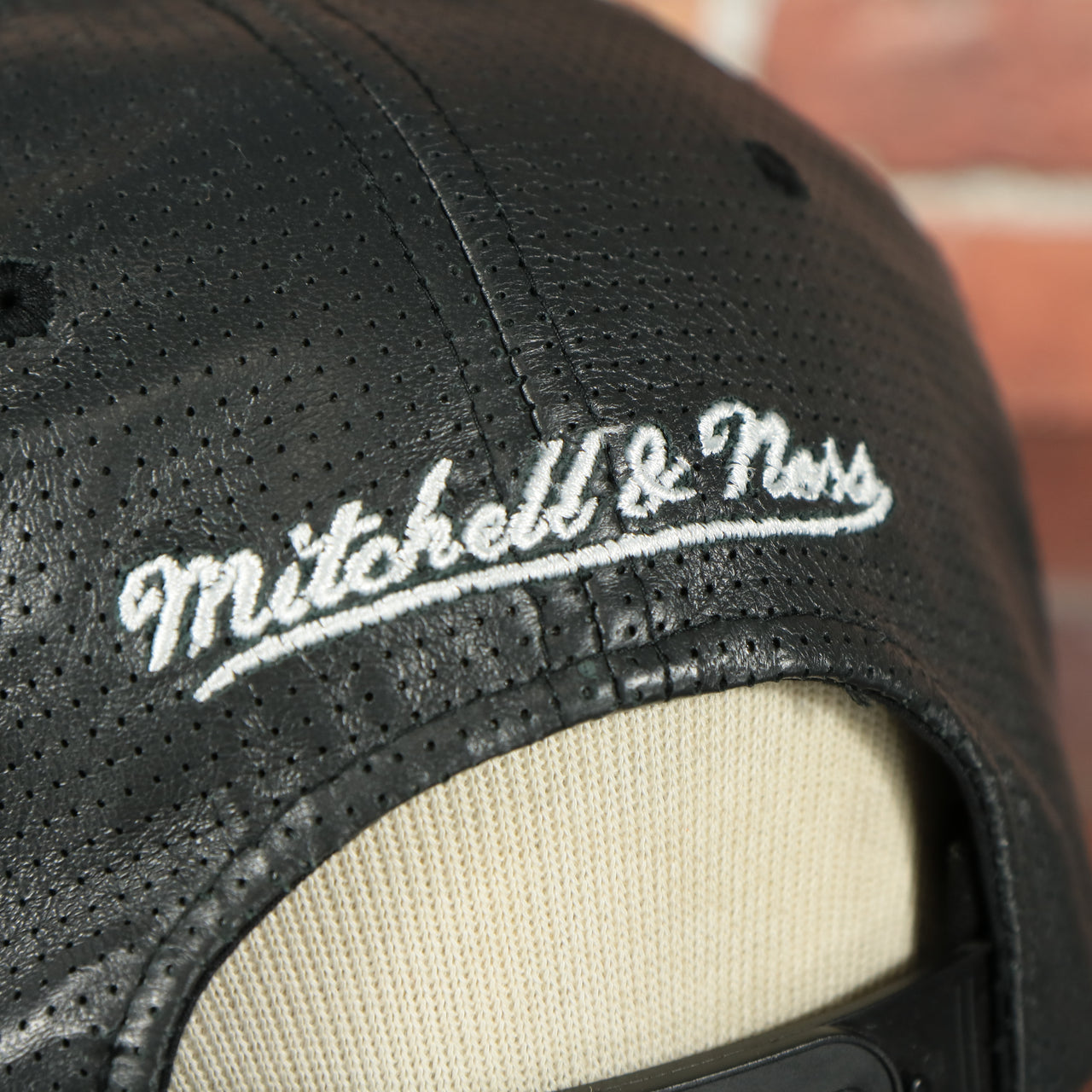 mitchell and ness logo on the Brooklyn Nets 100% Genuine Perforated Leather Mitchell and Ness Snapback Hat