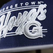 A Close up of the Hoyas Logo on the Georgetown Hoyas Team Script Gray Bottom 9Fifty Snapback | Navy Blue And Gray Snap Cap