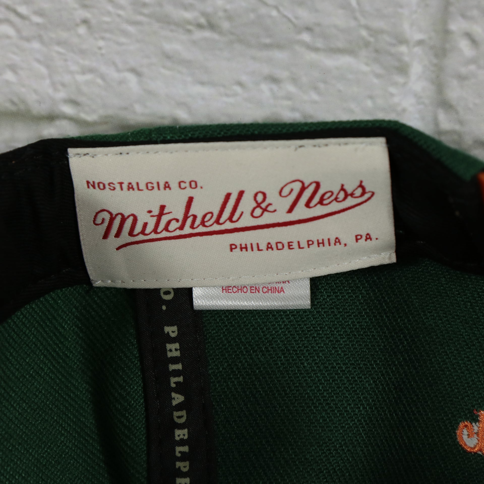 mitchell and ness label on the University of Miami Hurricanes Vintage Retro Sharktooth Mitchell and Ness Snapback Hat | Orange/Green