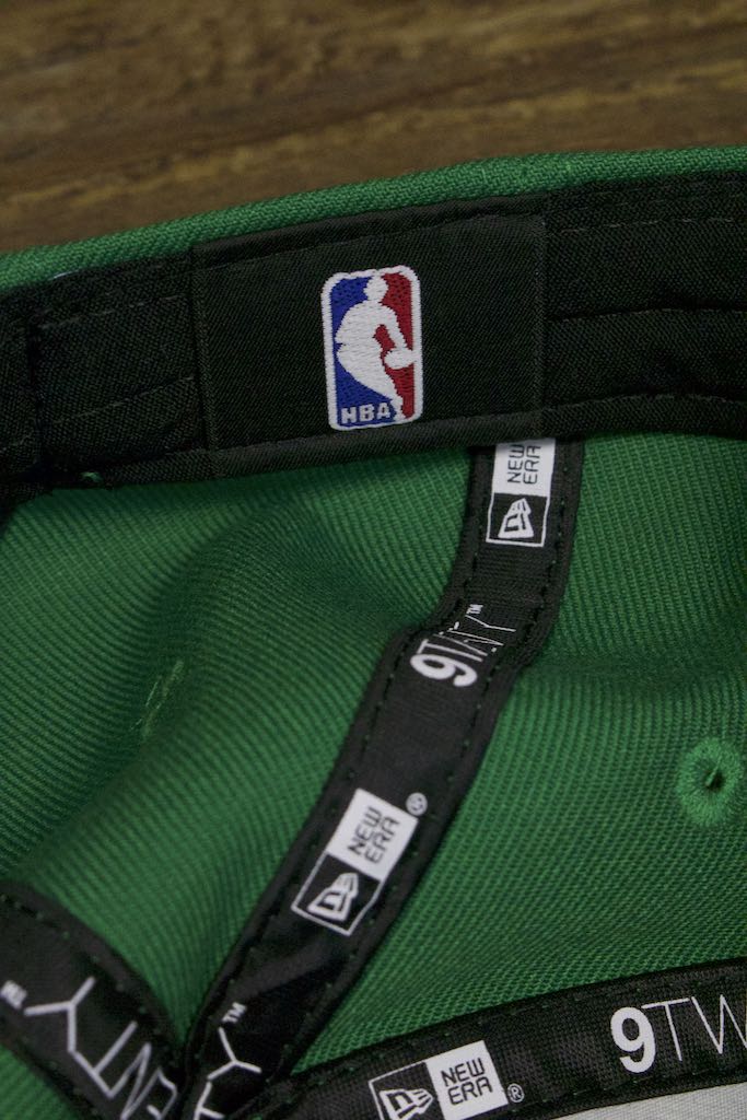 the inside of the Boston Celtics 2019 City Series Dad Hat | Irish Green Adjustable Boston Celtics Baseball Cap with Golden Shamrock has the NBA logo on a black sweatband